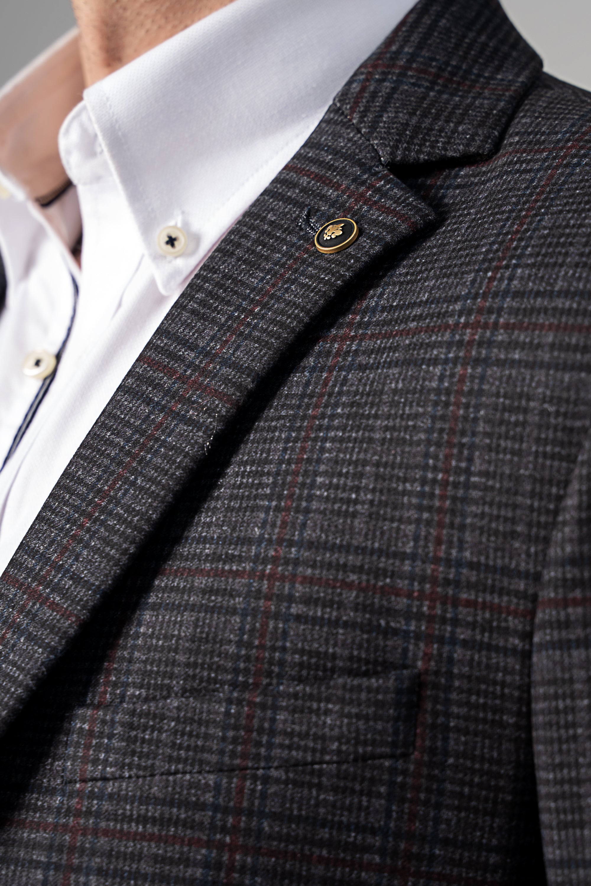 Grey check casual coat detail: lapel pin, button closure, textured weave fabric.