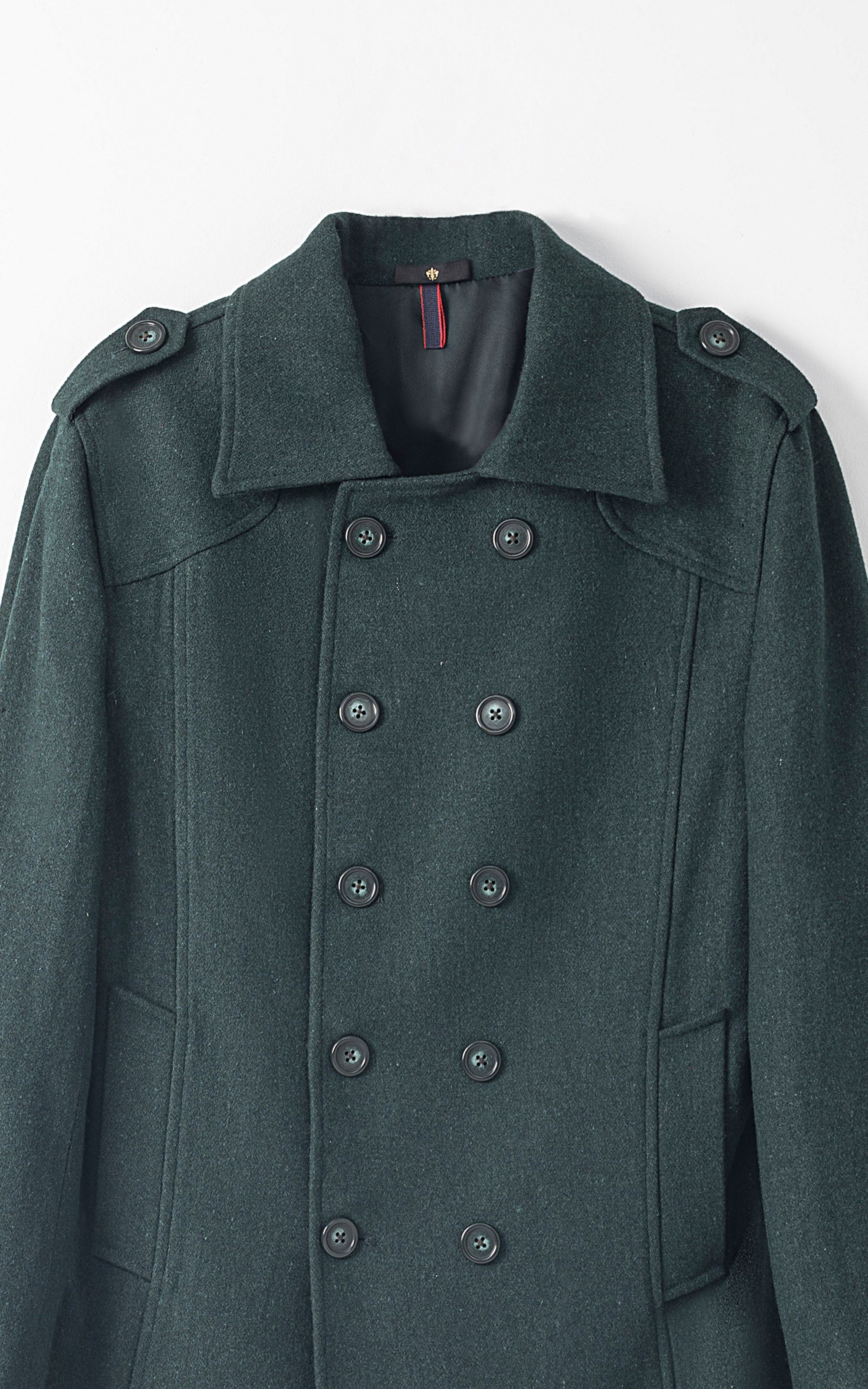 Long coat close-up in dark teal with structured double-breasted buttons and notch lapels