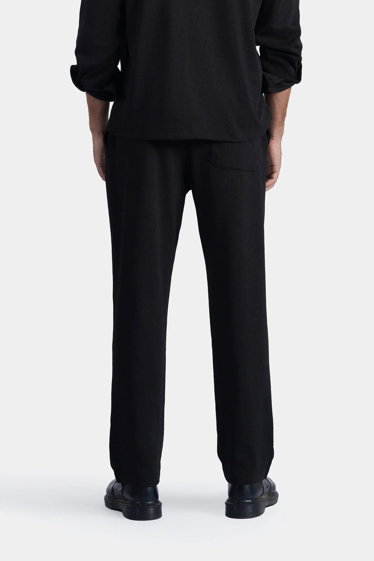 Loose-fit black trousers, back view with relaxed seat and straight legs