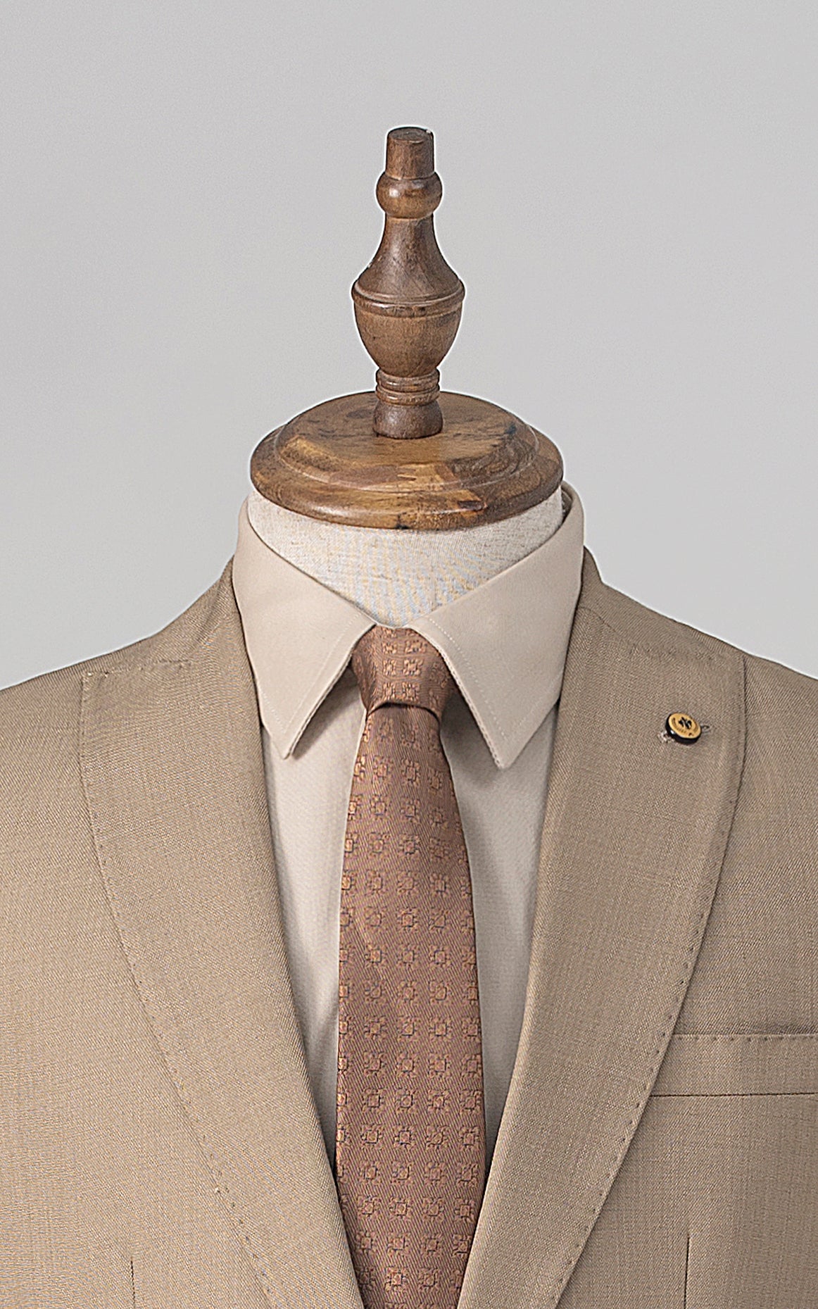 Khaki suit jacket with notch lapel and one gold button, paired with patterned tie