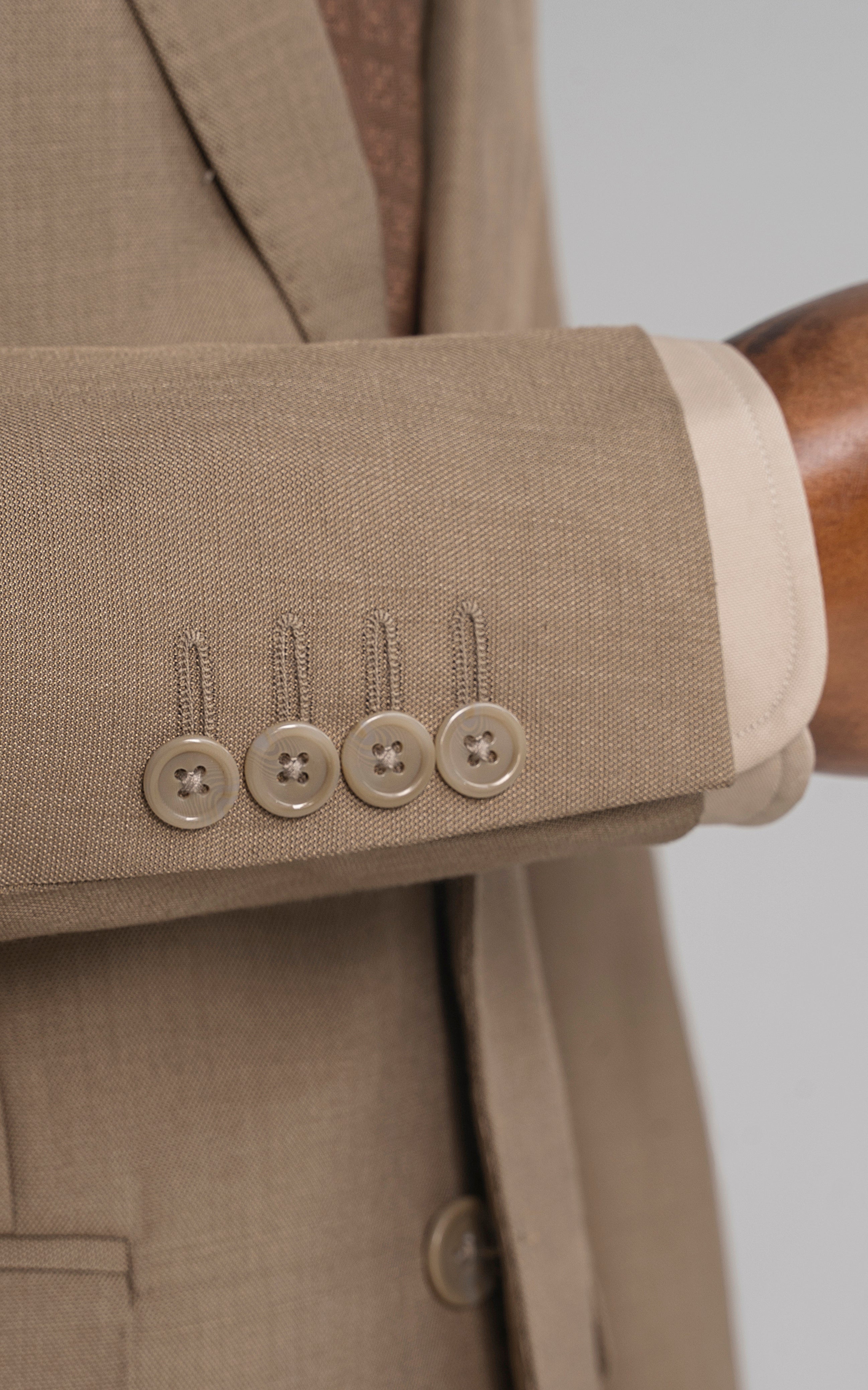 Khaki suit sleeve cuff with four buttons and white shirt cuff peeking