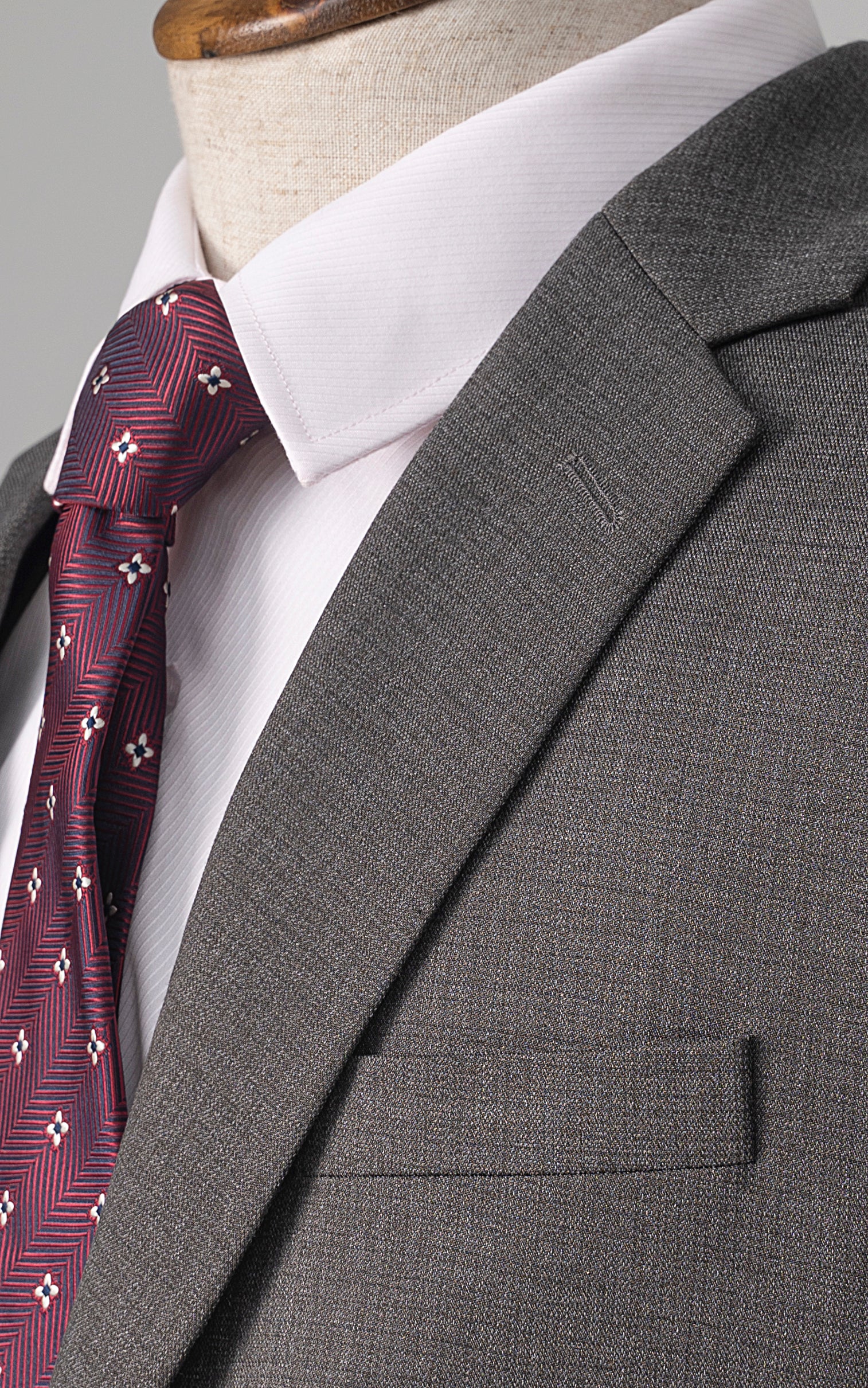 Grey suit jacket shoulder and lapel with maroon patterned tie and white shirt