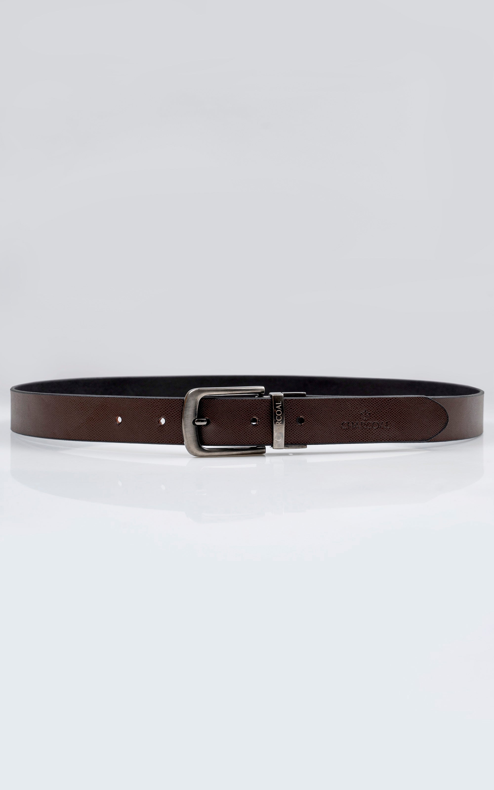 Reversible leather belt laid flat, brown side facing up with silver buckle and stitched strap.