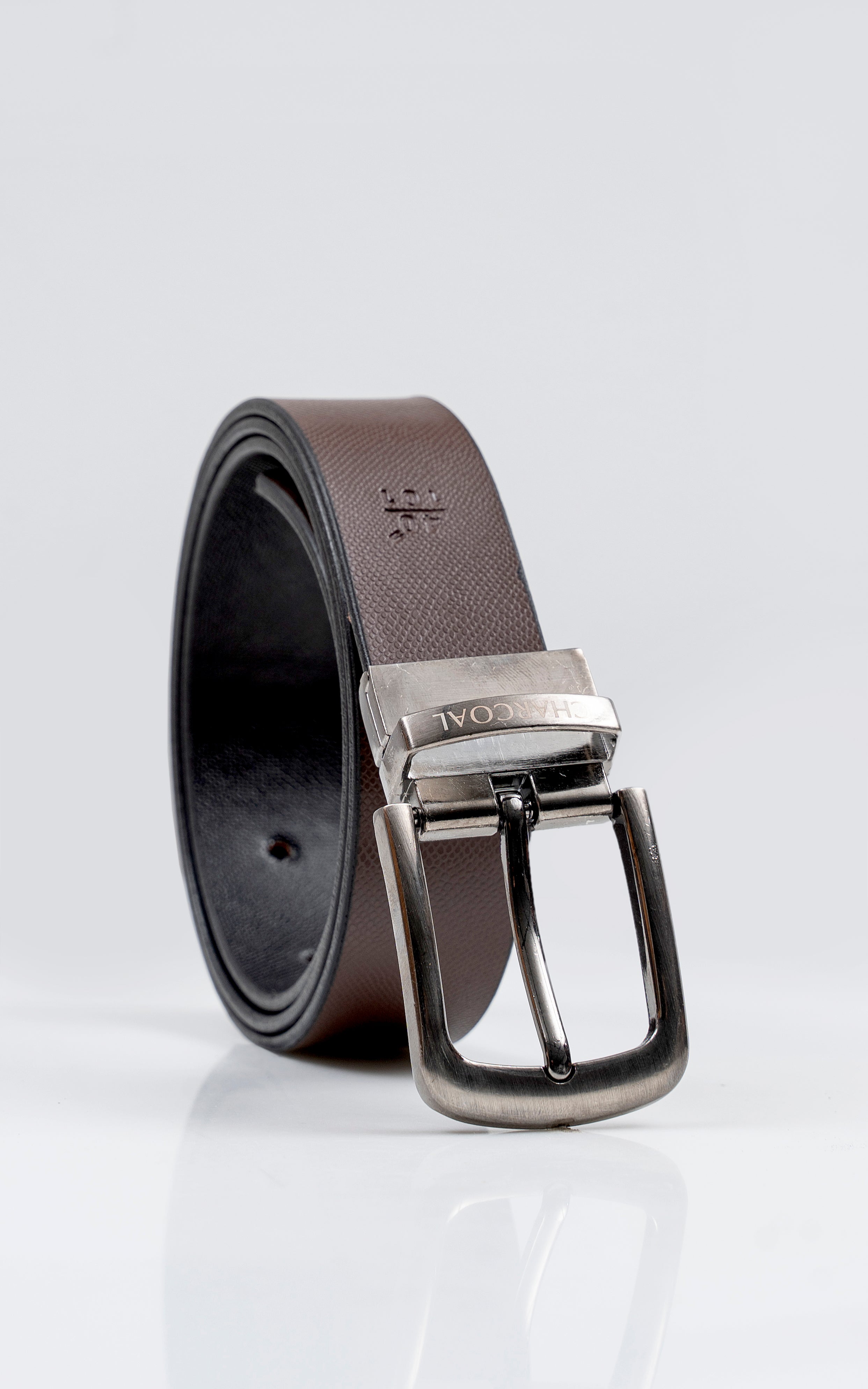Reversible leather belt with silver buckle, shown rolled with dark underside and brown strap.