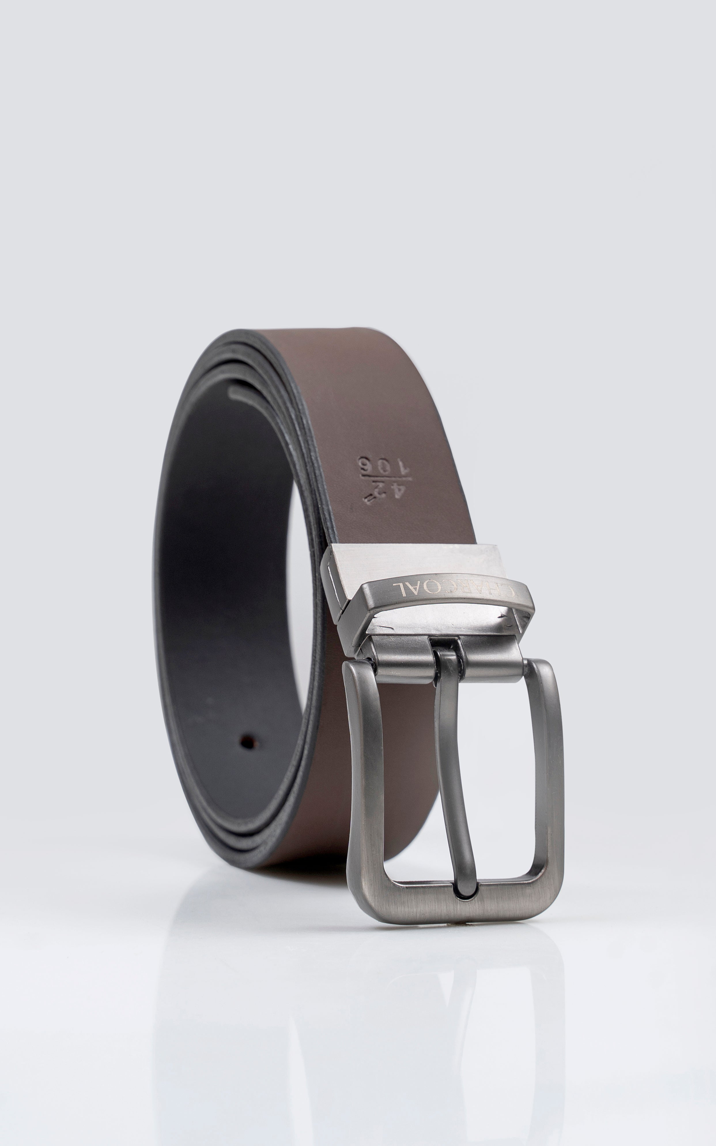 Reversible belt rolled up with dark brown strap, black underside, and silver buckle