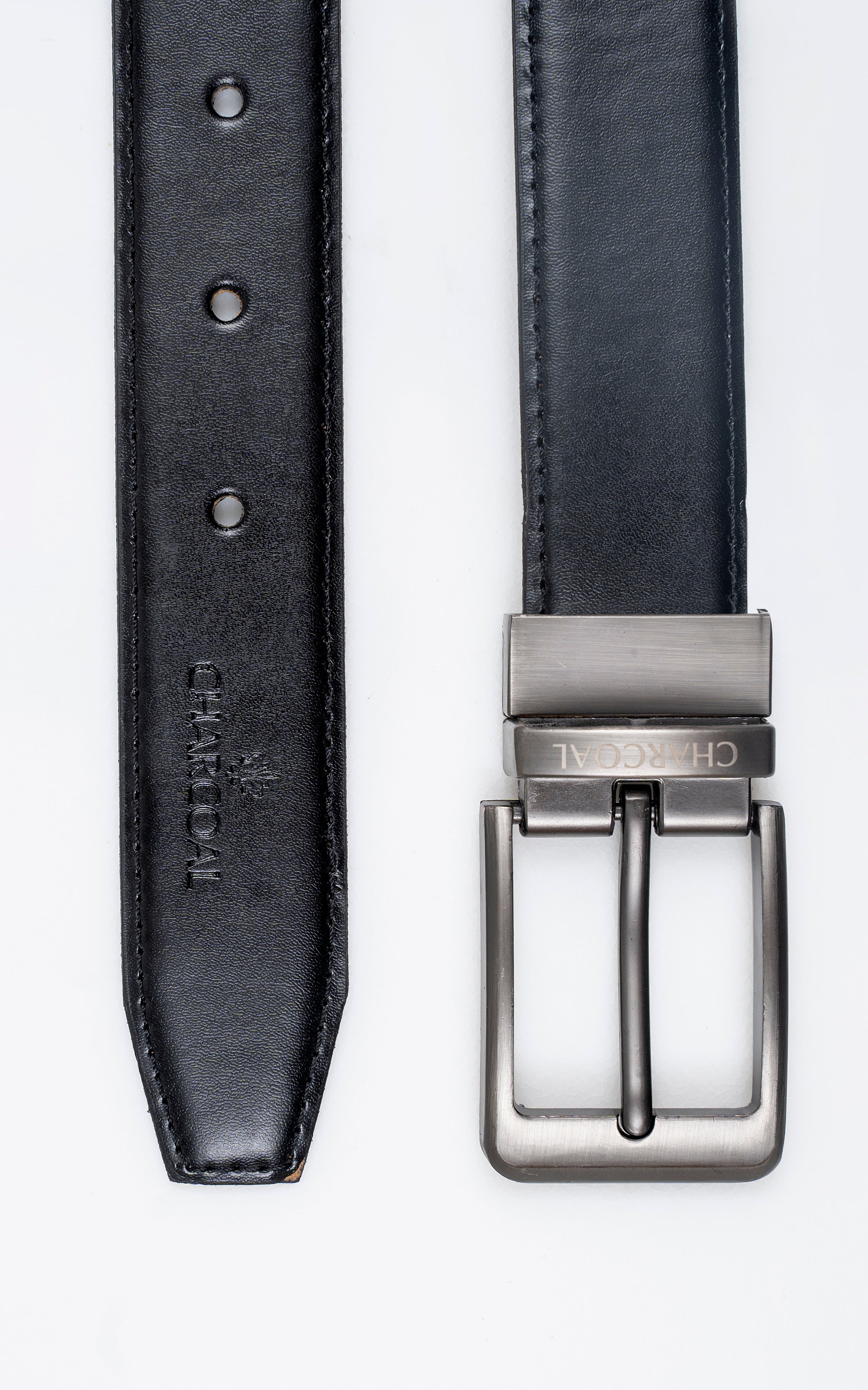 Leather belt close-up: punched adjustment holes and reversible strap near silver buckle