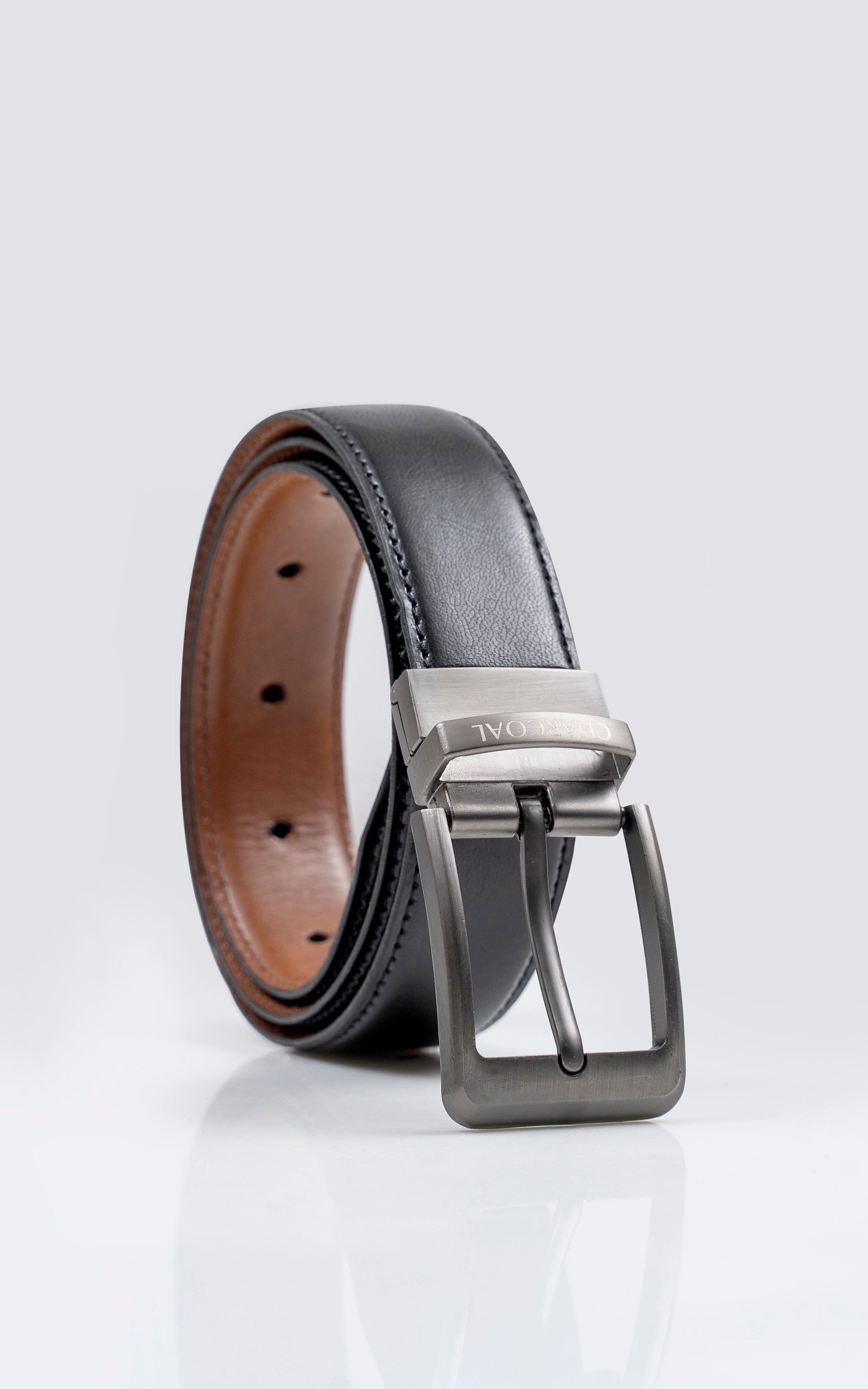 Reversible leather belt with black side, silver buckle, and punched holes.