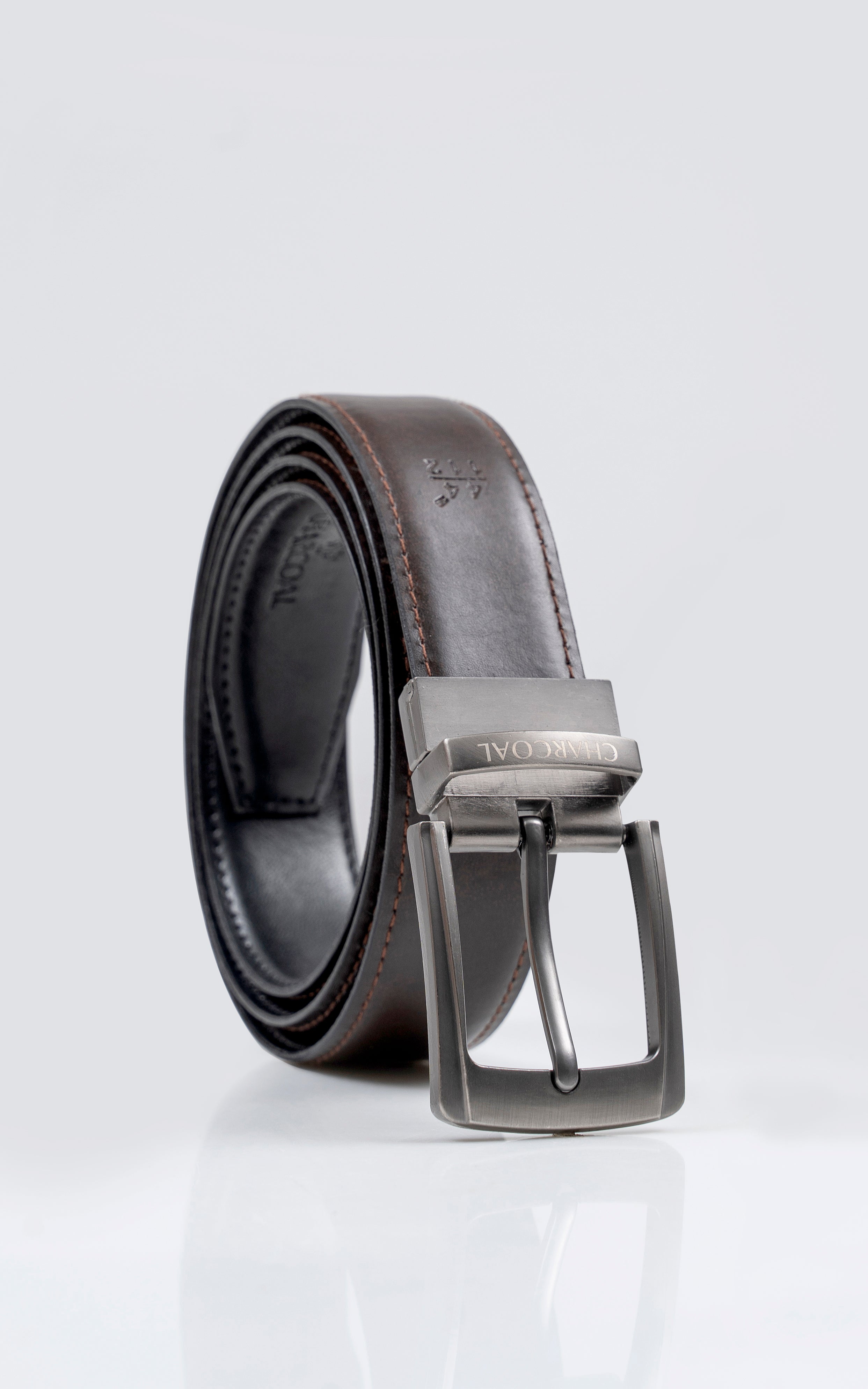 Rolled reversible leather belt showing dark and brown sides with silver buckle