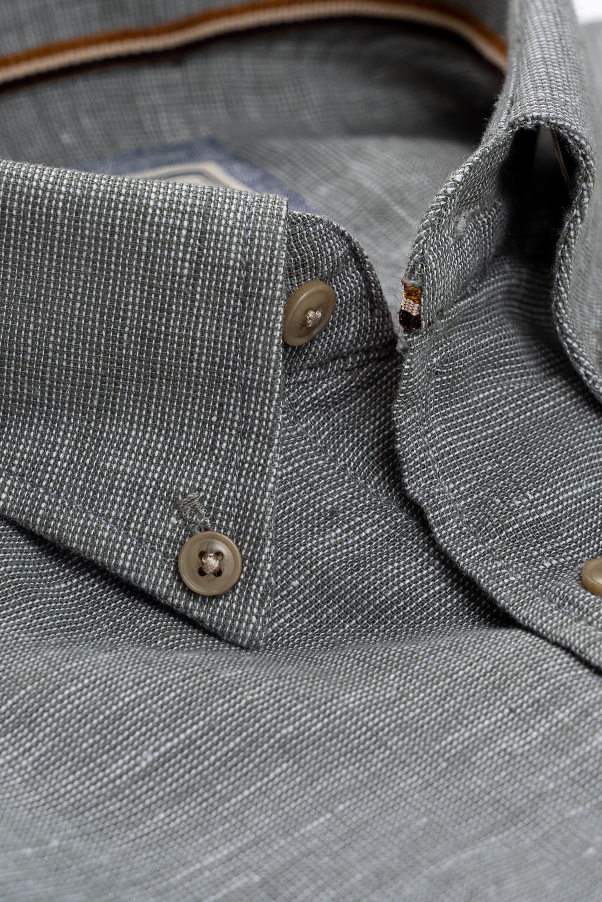 Close-up of textured linen shirt placket with brown buttons and collar