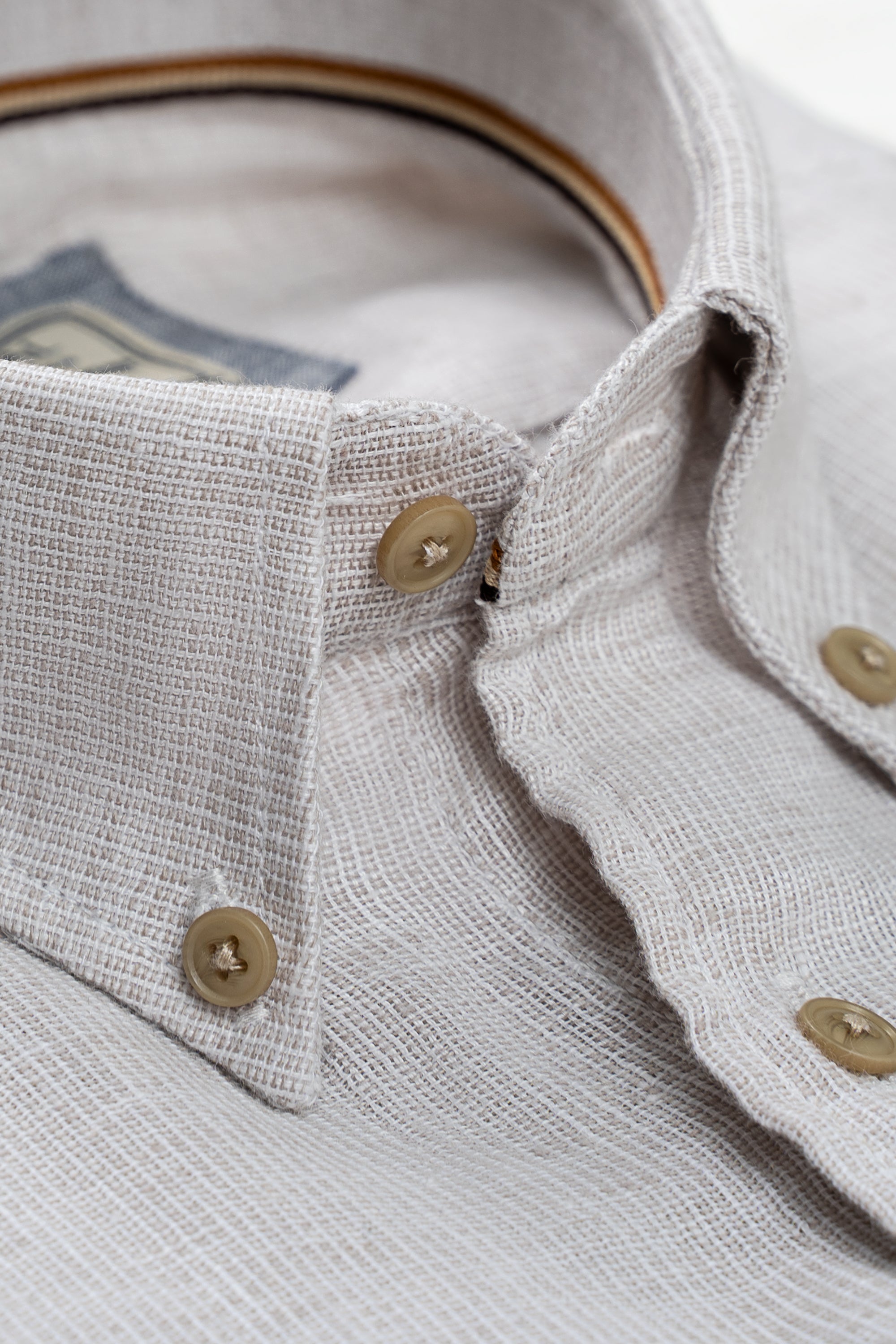 Linen shirt neckline and placket detail with gold buttons and tan inner collar
