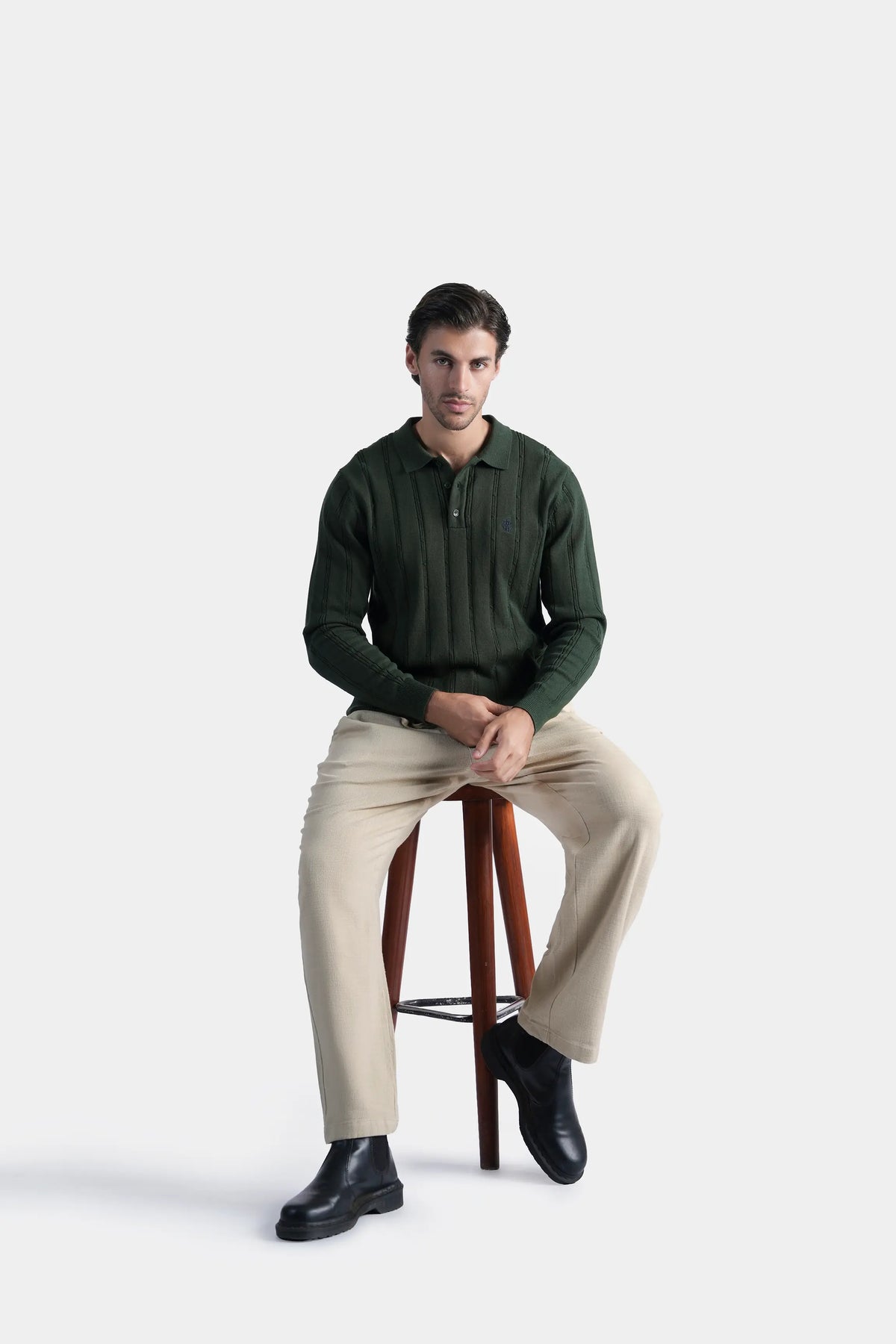 Men's dark green cable knit sweater with button front and long sleeves, seated