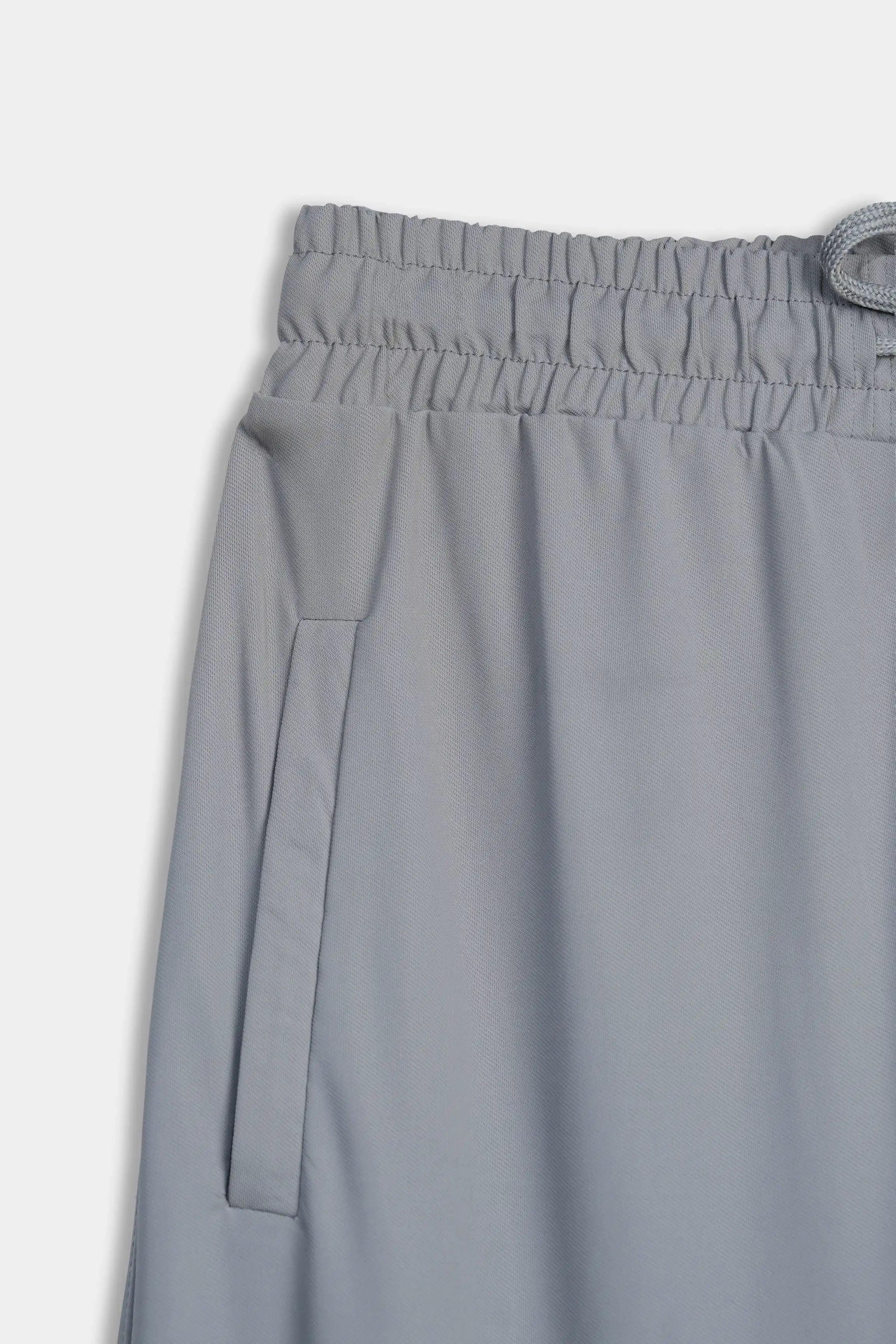 Grey trousers waistband detail with elastic and drawstring loop, side pocket at thigh.