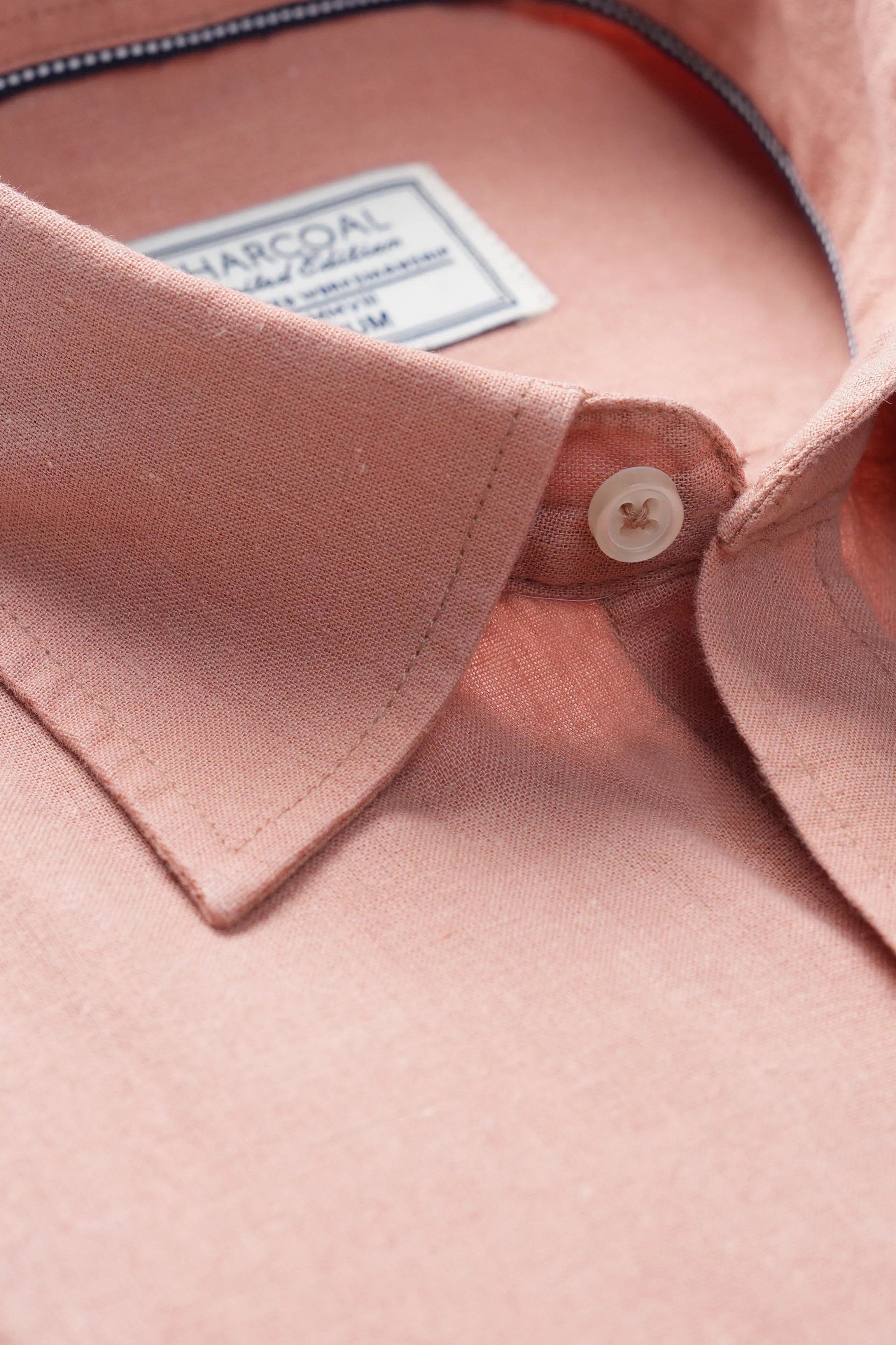 Peach linen collar and button placket close up with stitched inner label