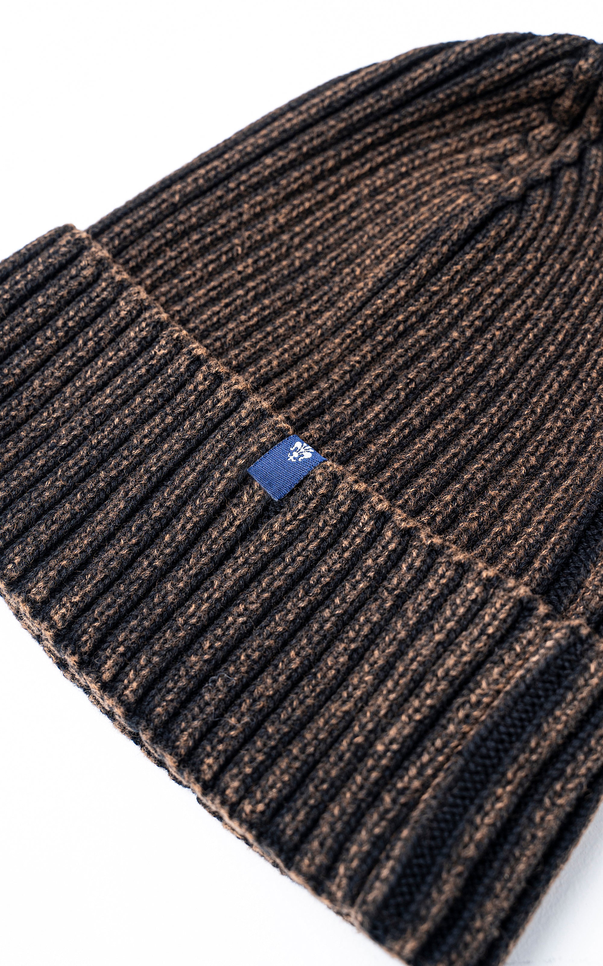 Ribbed wool beanie cuff with small blue brand patch near the edge
