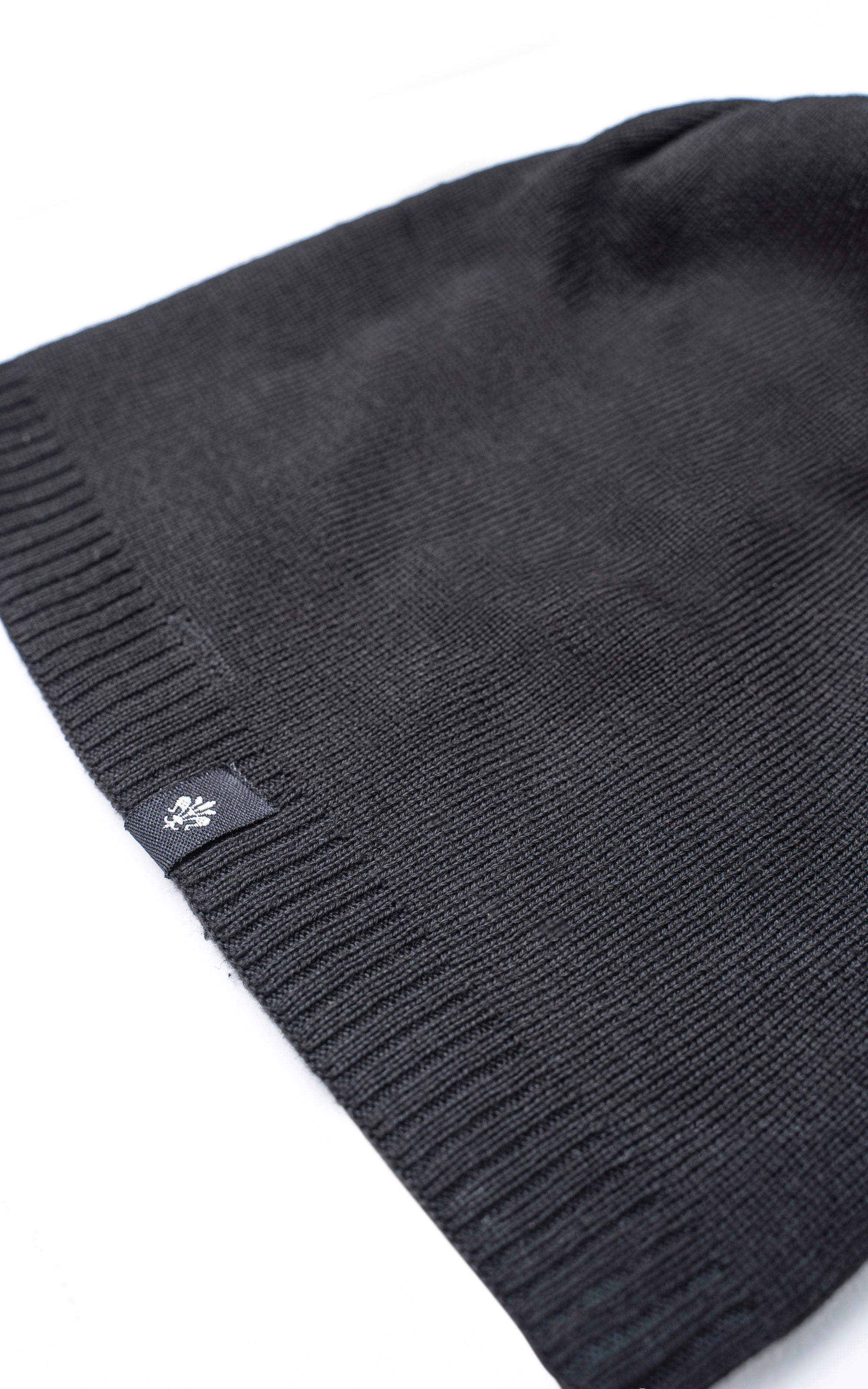 Dark charcoal wool beanie with ribbed cuff and small white flower logo