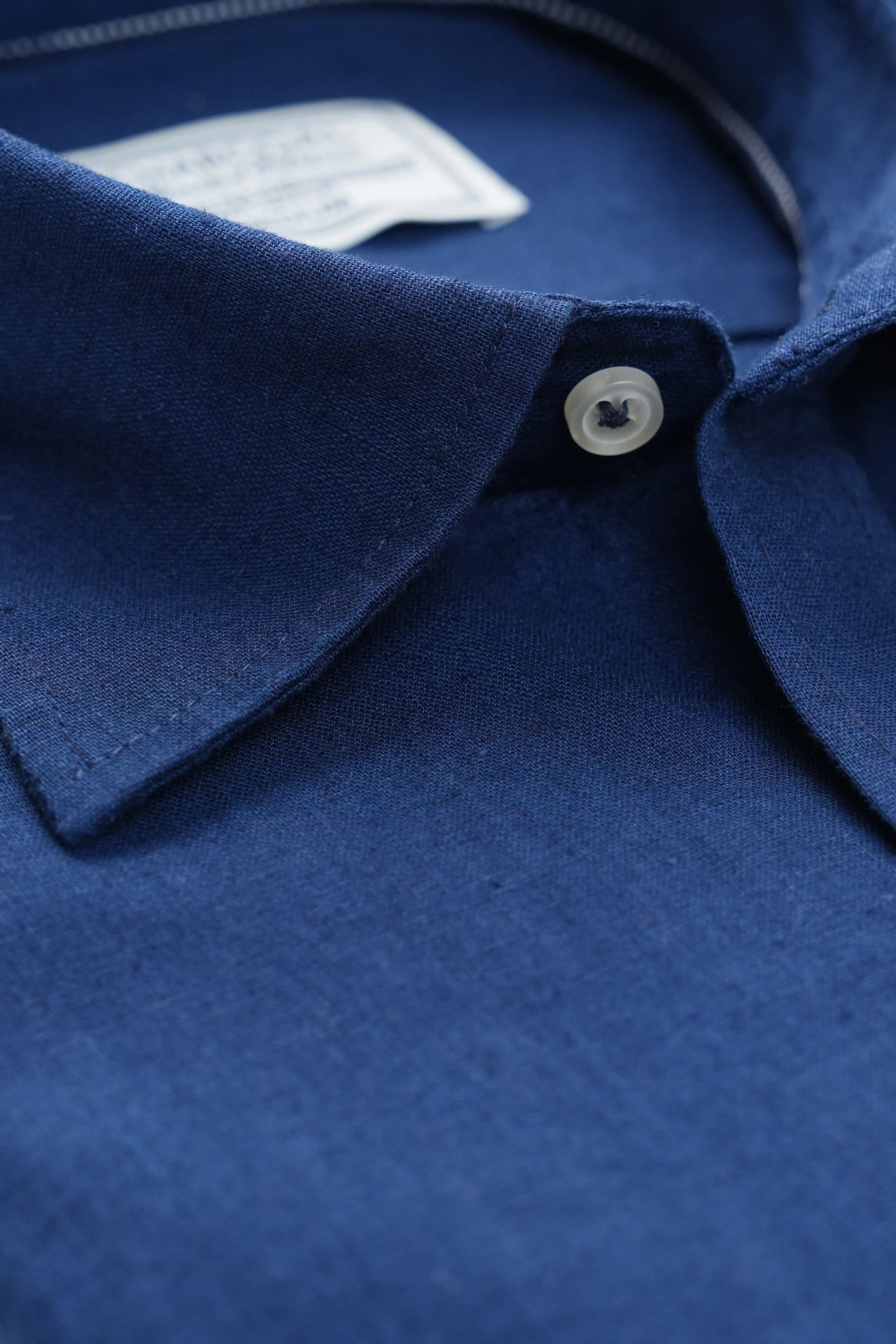 Navy linen shirt collar detail with white button and button placket