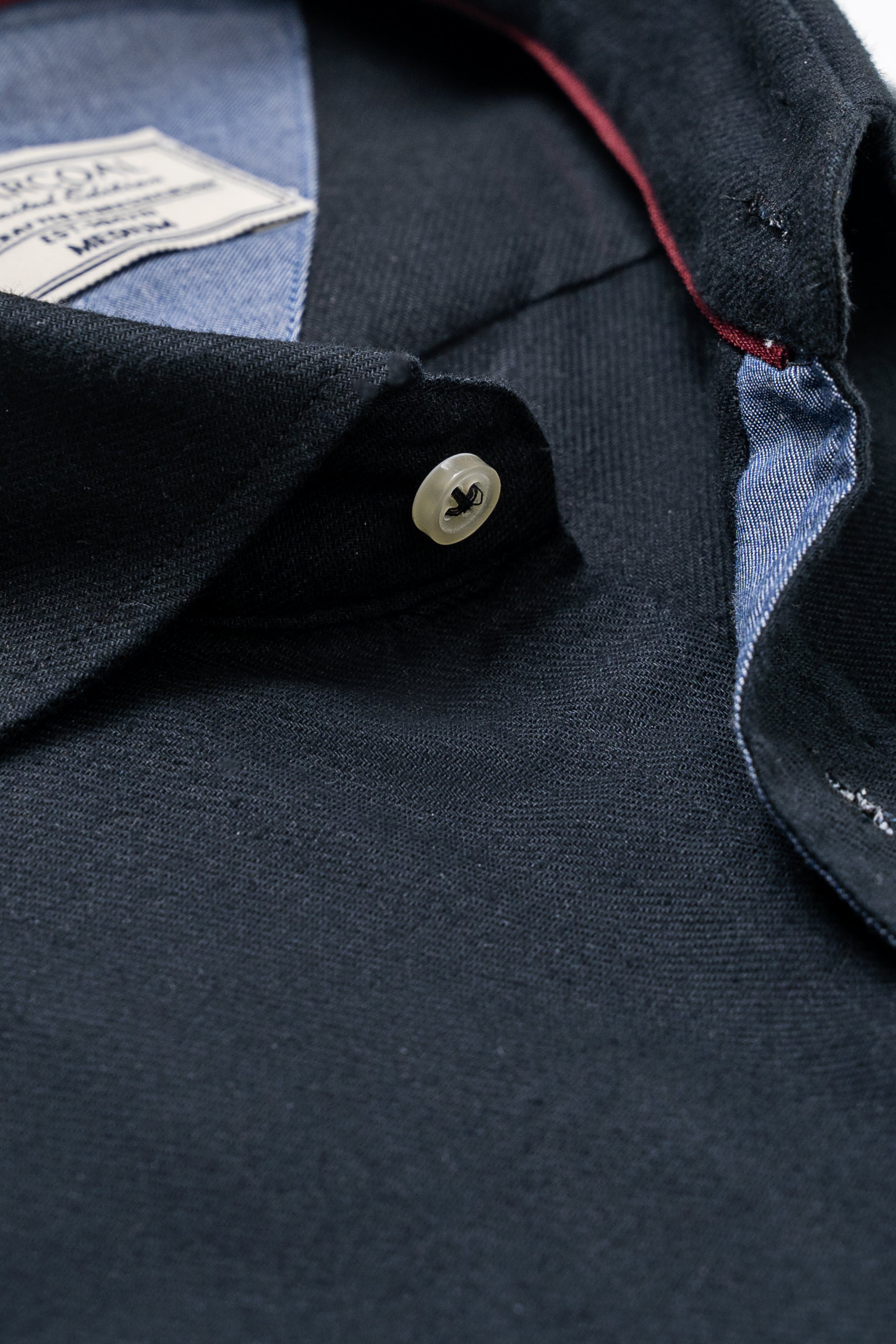 Shirt collar and button placket close-up with dark fabric and red inner trim