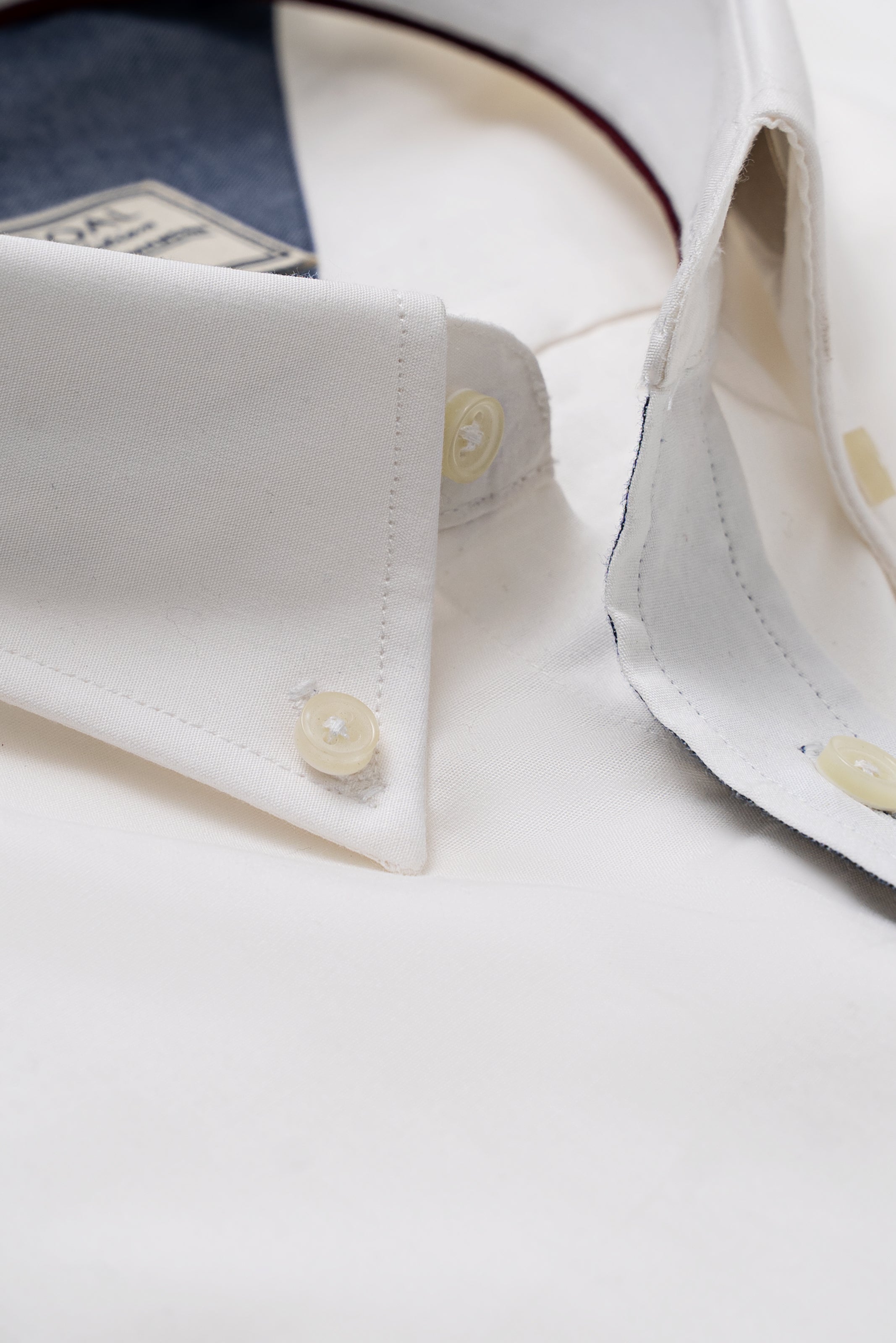 White shirt collar and placket close-up with gold buttons and visible stitching