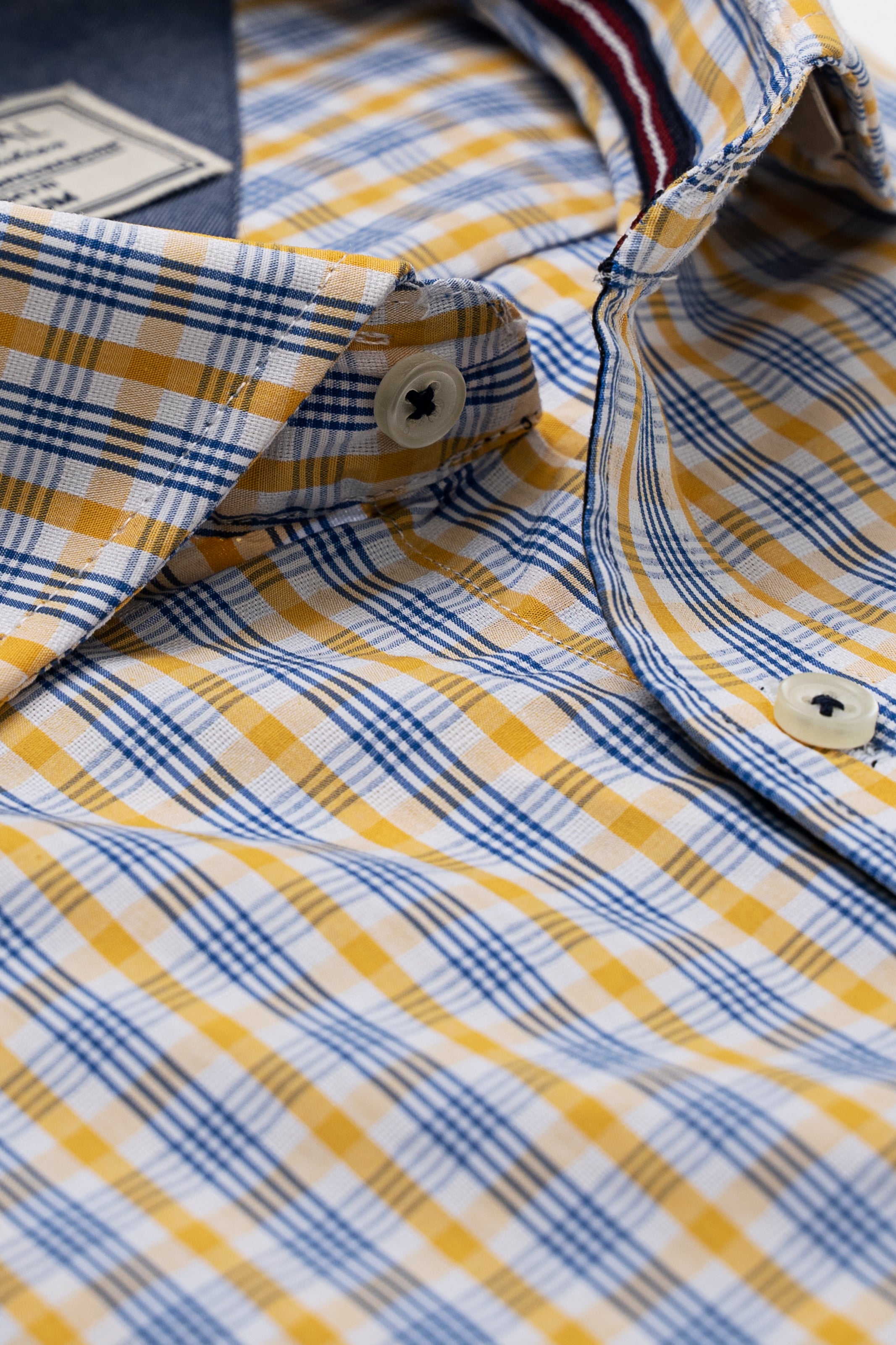 Limited edition check shirt collar close-up with blue and mustard plaid buttons