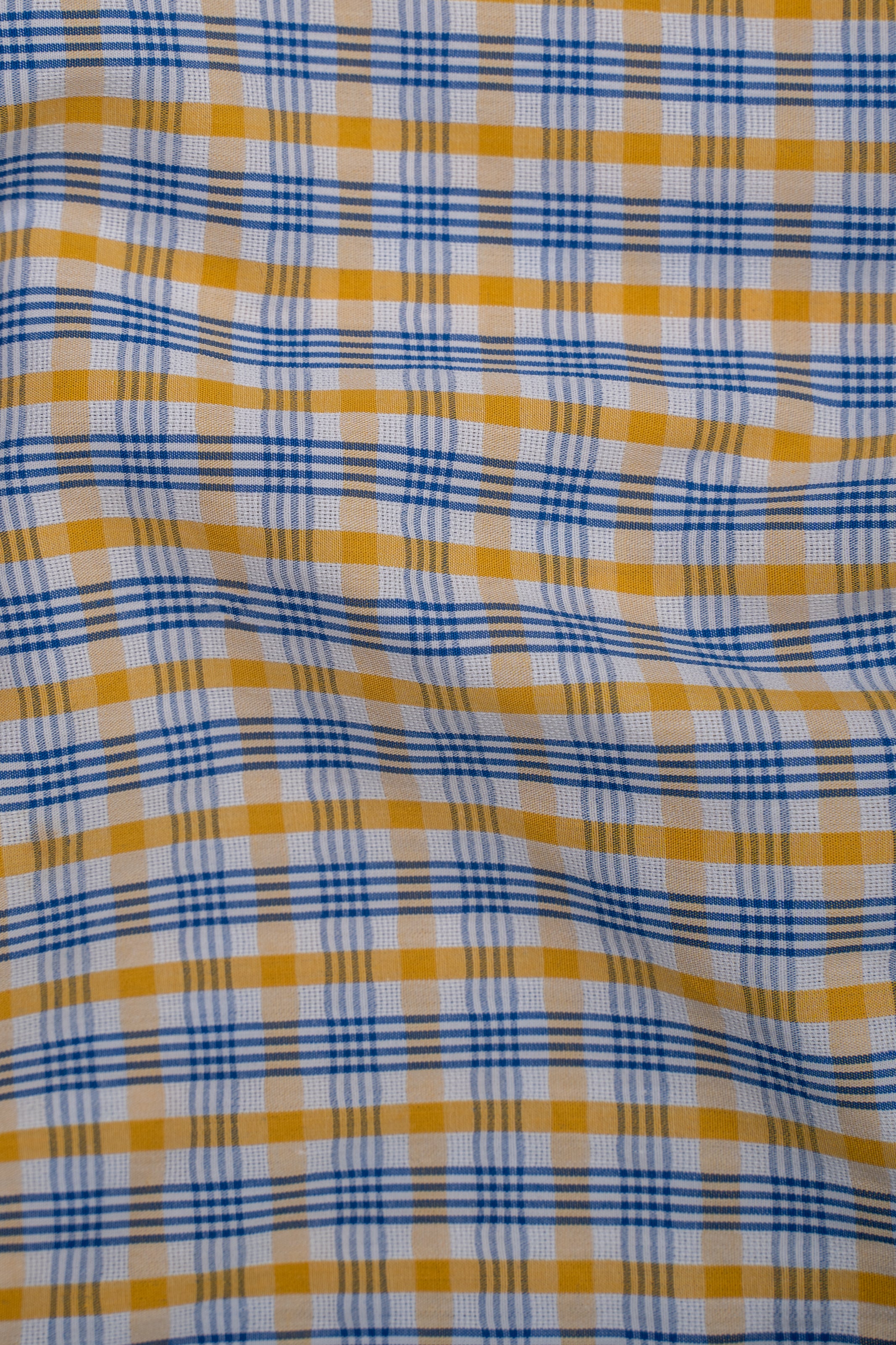 Limited edition check shirt fabric close-up in blue and mustard plaid
