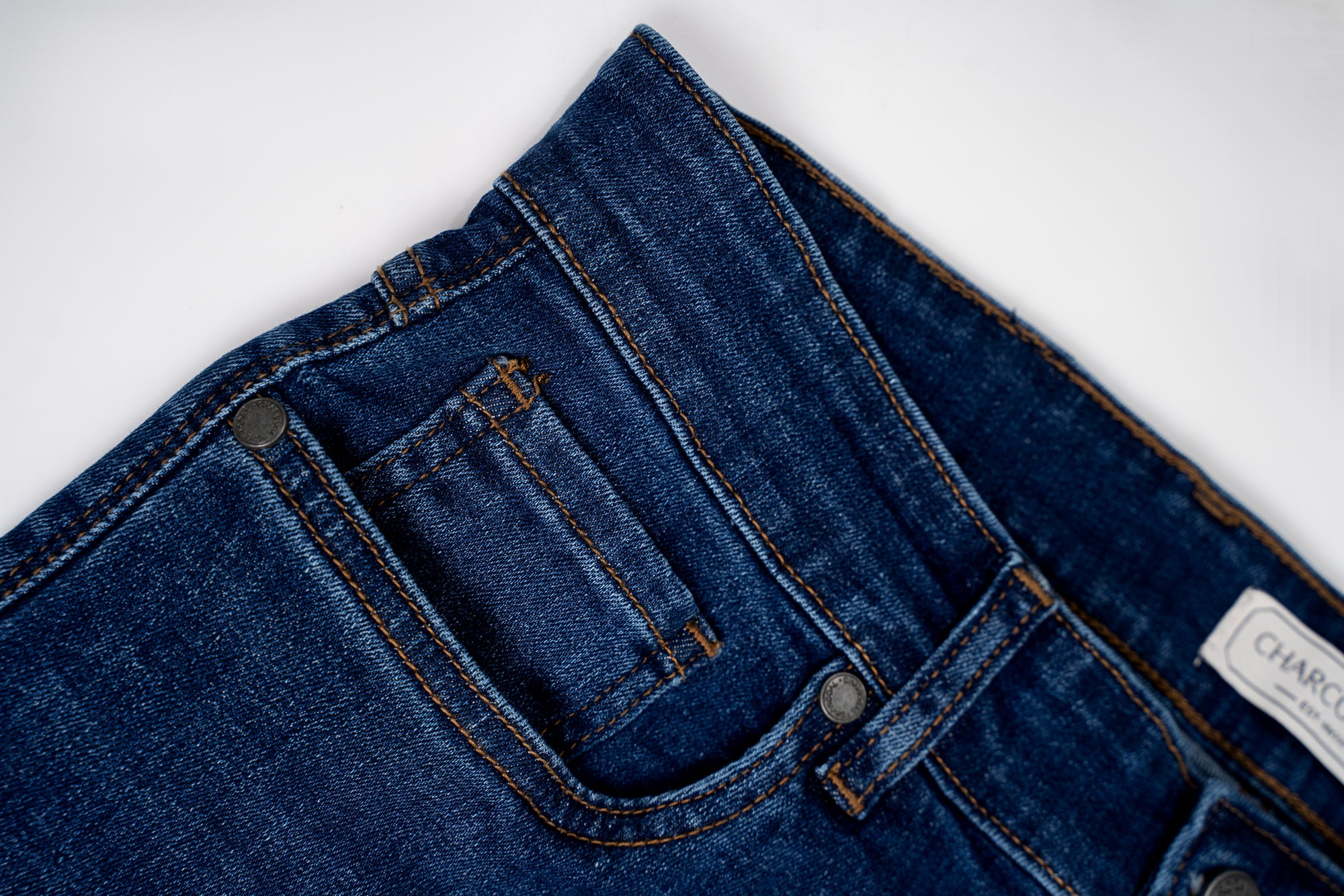 Mid blue denim jeans waistband and front pocket detail with stitched seams and buttons