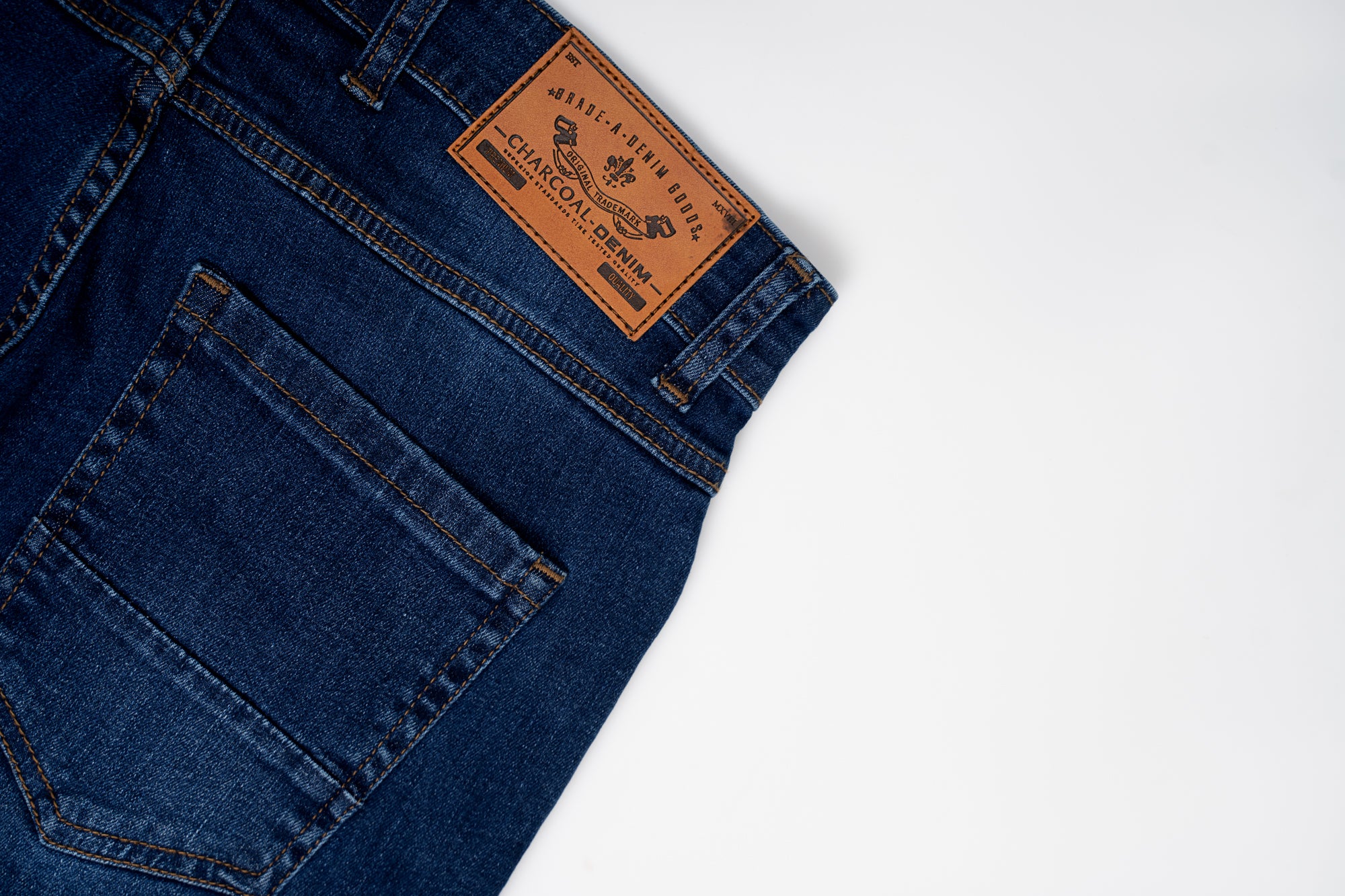 Mid blue denim jeans with front pocket and tan leather brand patch on waistband