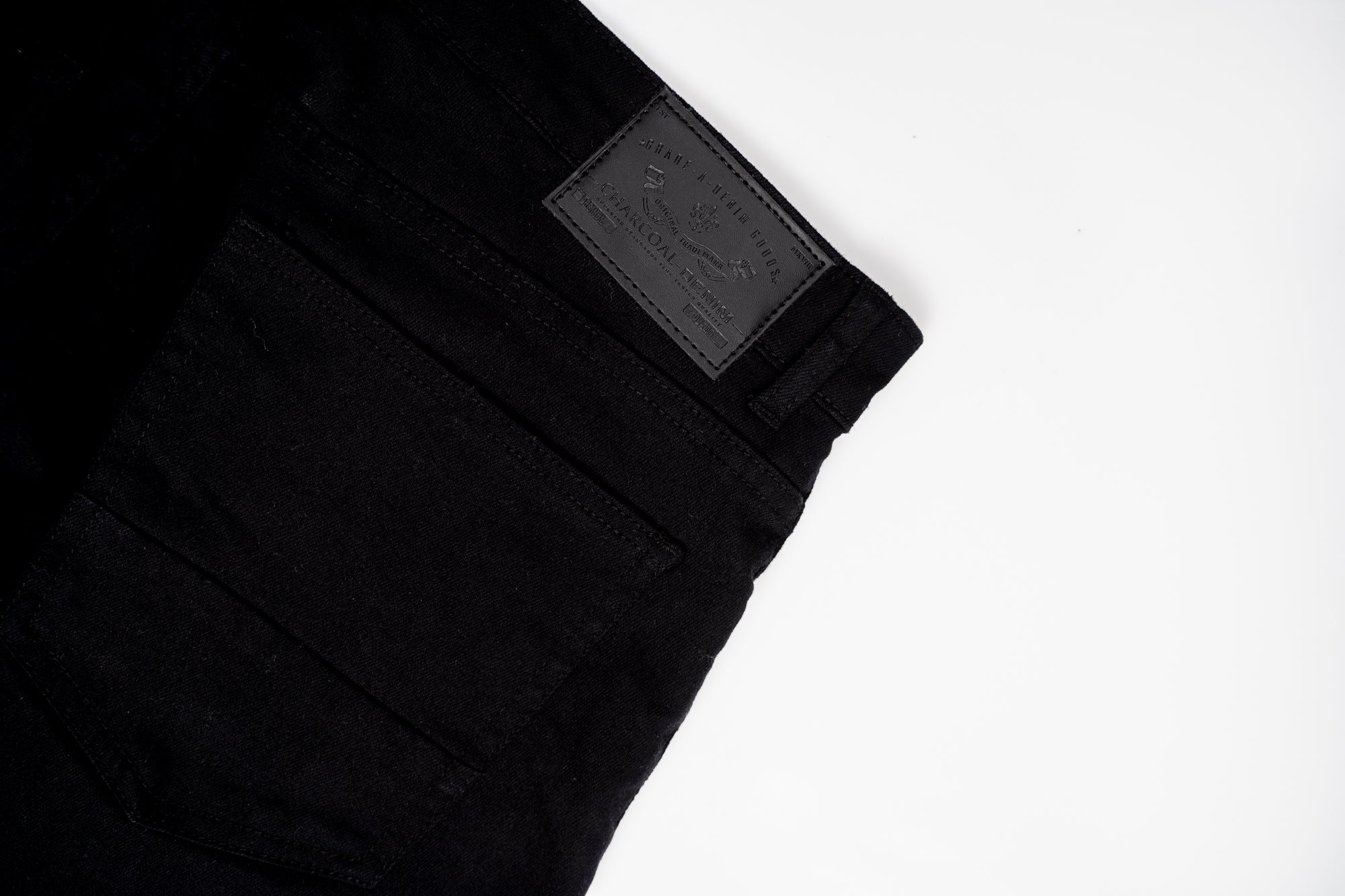 Black jeans leg with woven brand label and visible seam stitching