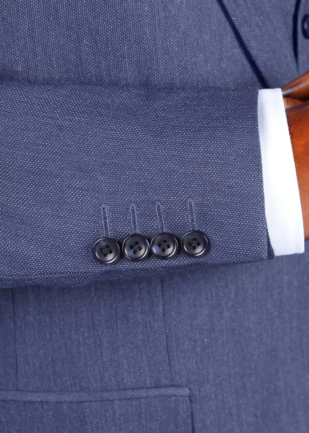 Teal blue jacket sleeve cuff with four dark buttons and stitched placket.