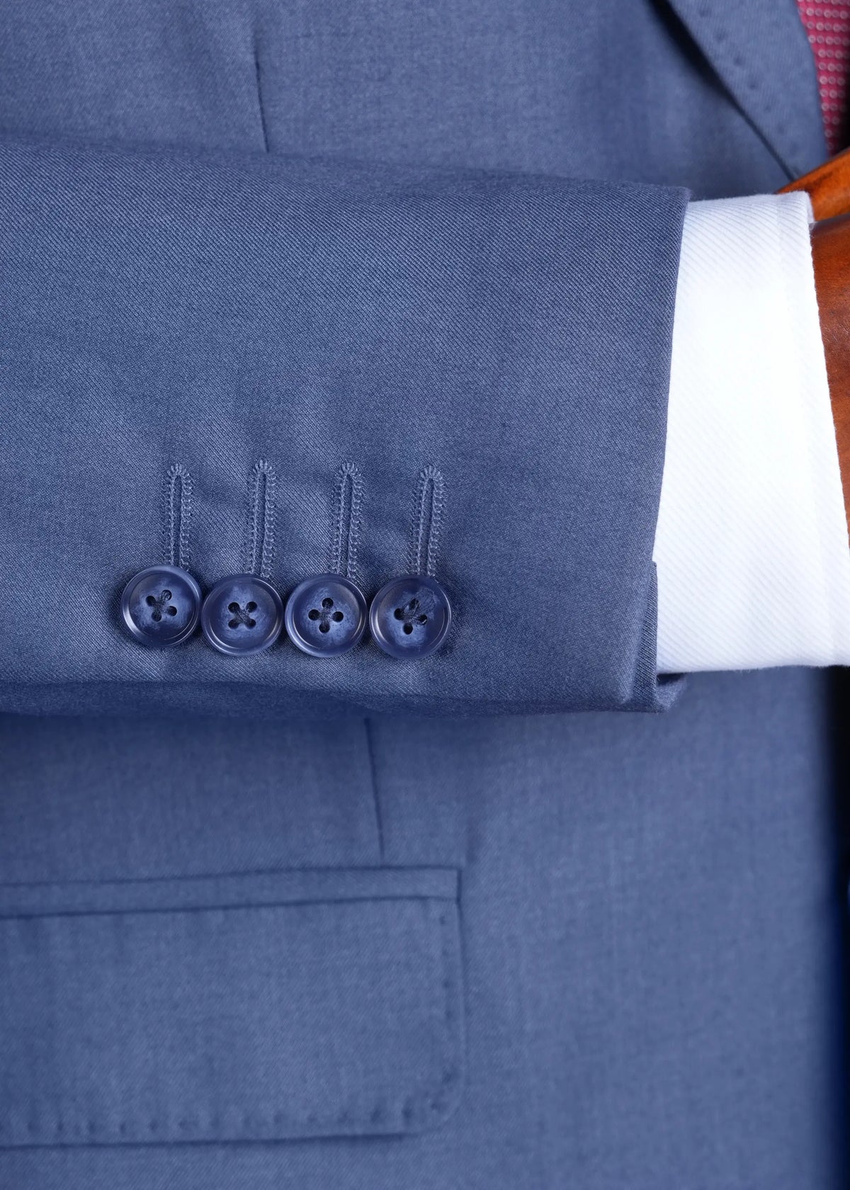 Bluish grey suit jacket sleeve cuff with four-button placket, close-up.