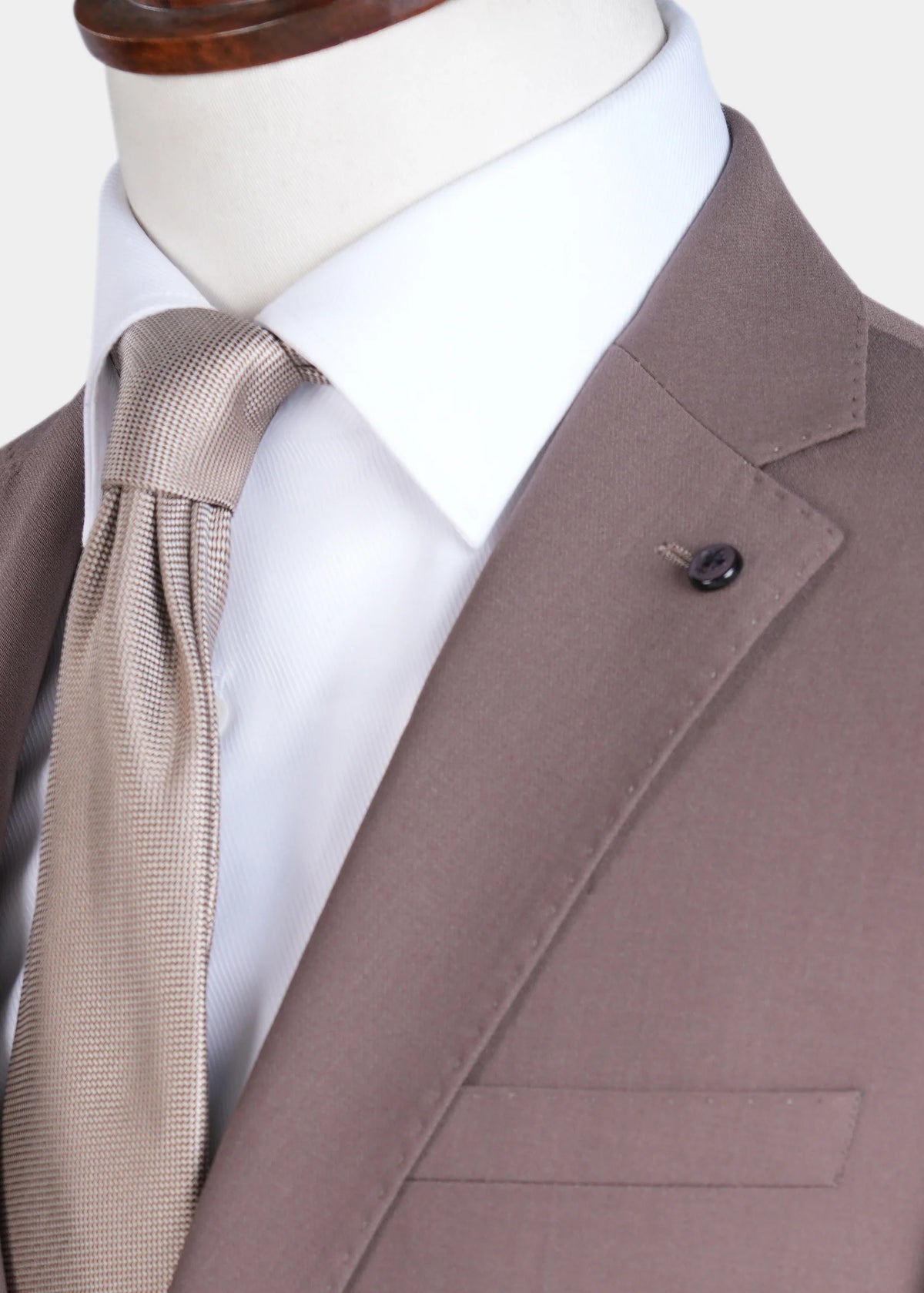 Brown suit jacket detail with patterned tie and decorative lapel pin