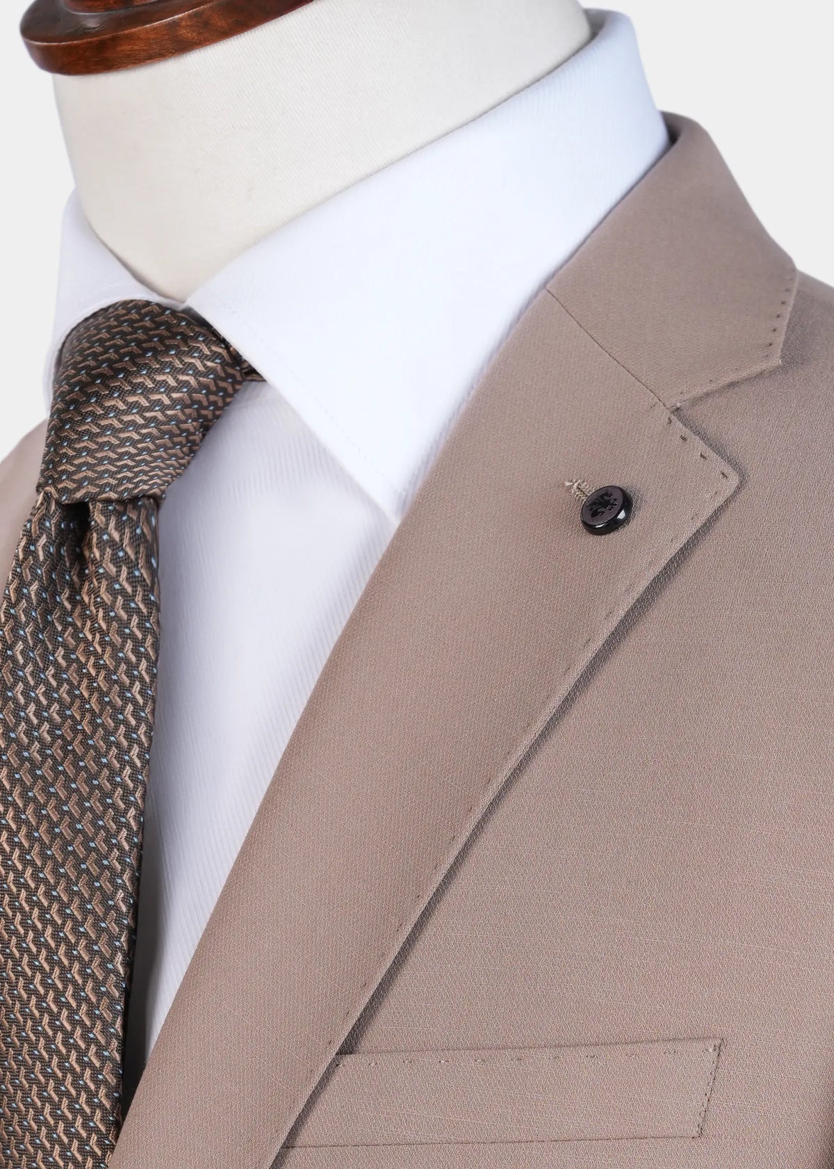 Light brown suit jacket lapel and breast pocket, with dark patterned necktie close-up