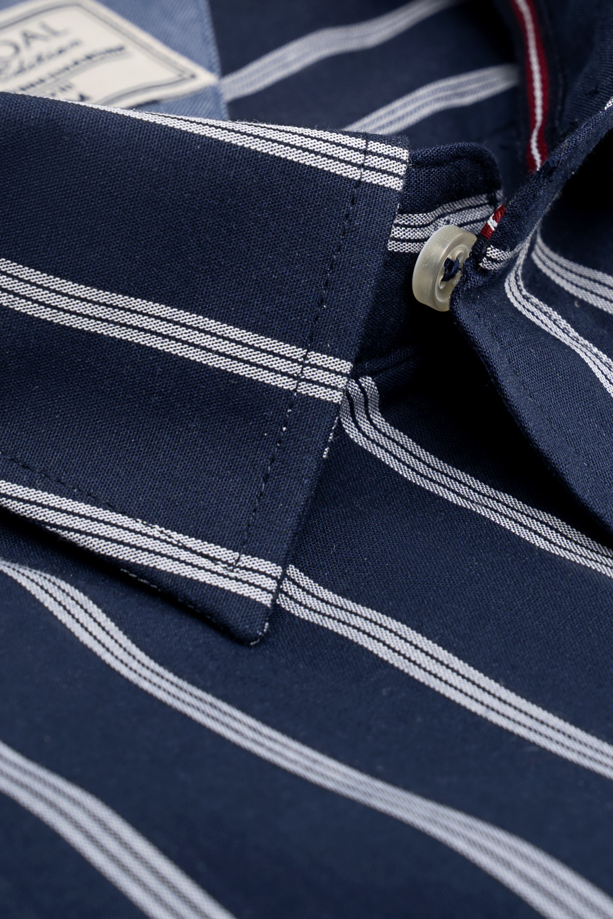Striped shirt cuff closeup with navy fabric, white stripes, and buttoned placket
