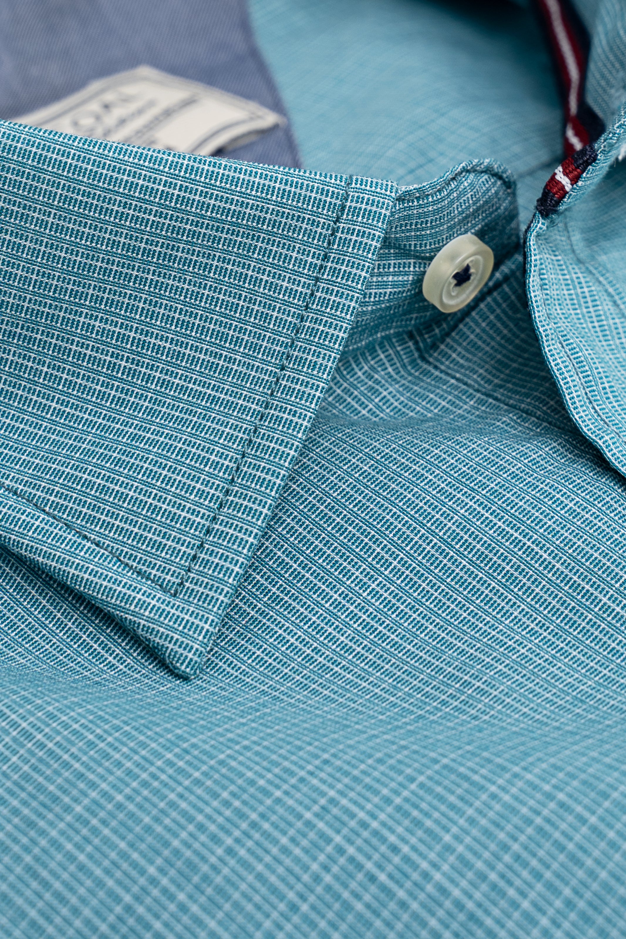 Aqua green dress shirt close-up: woven fabric, cuff seam, and round button
