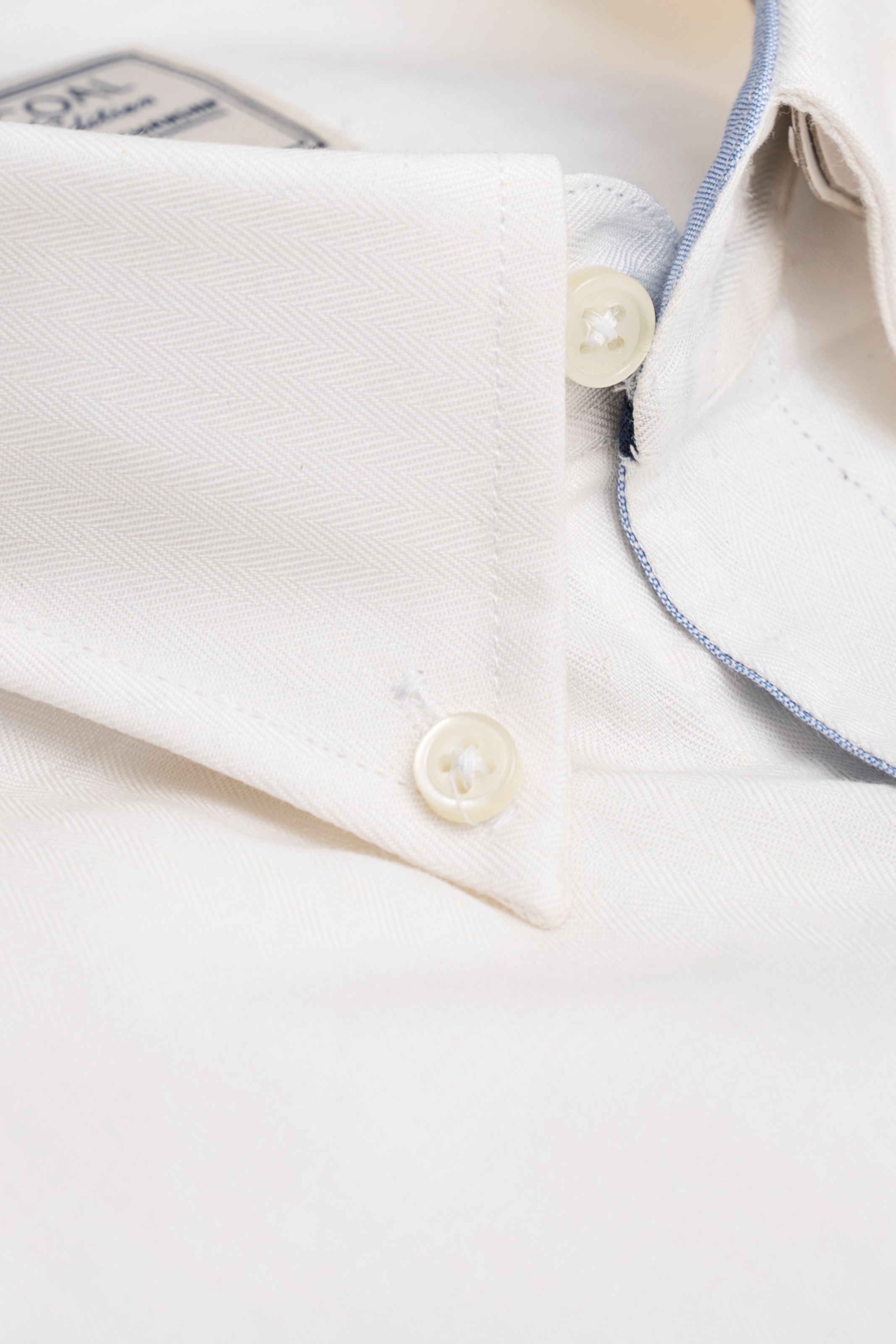 Off-white shirt cuff with gold-toned button and textured woven fabric