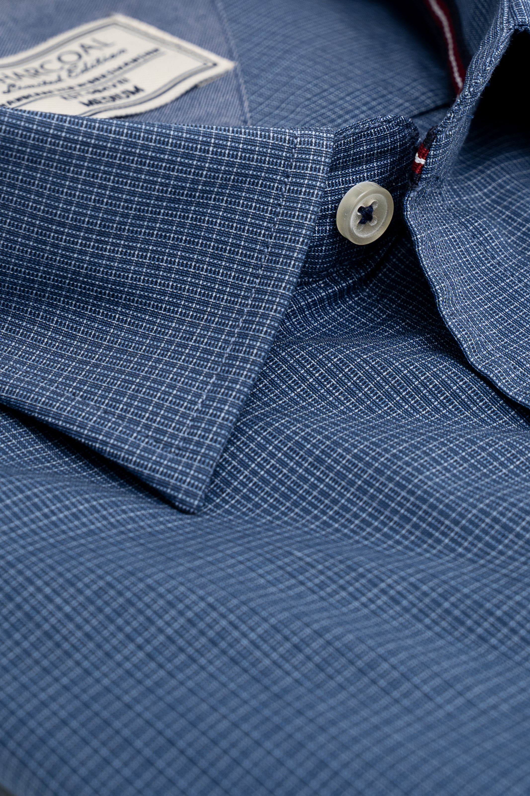 Dark blue dress shirt close-up with white button and buttoned placket