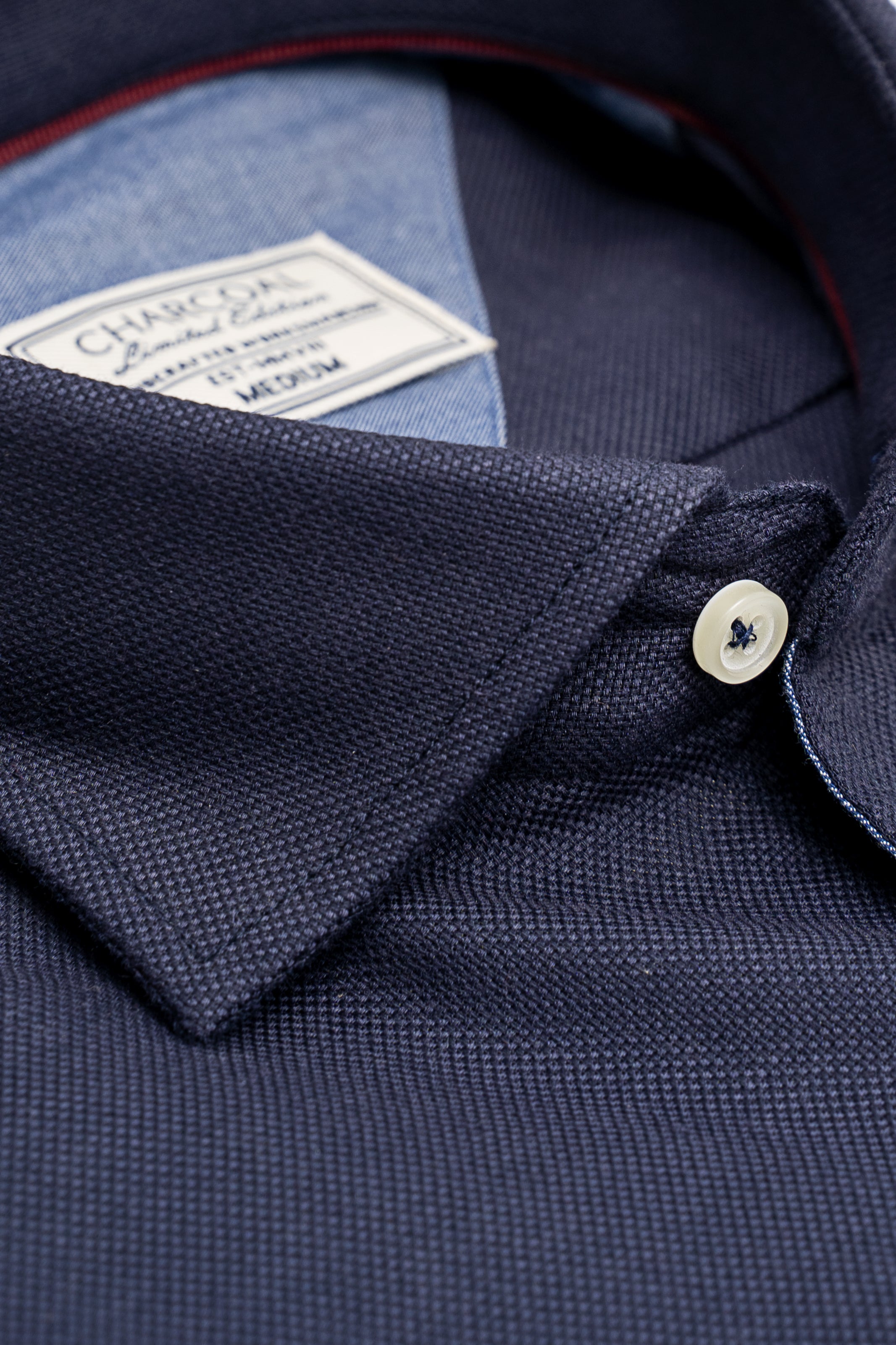 Navy dress shirt collar close-up with buttoned placket and woven texture