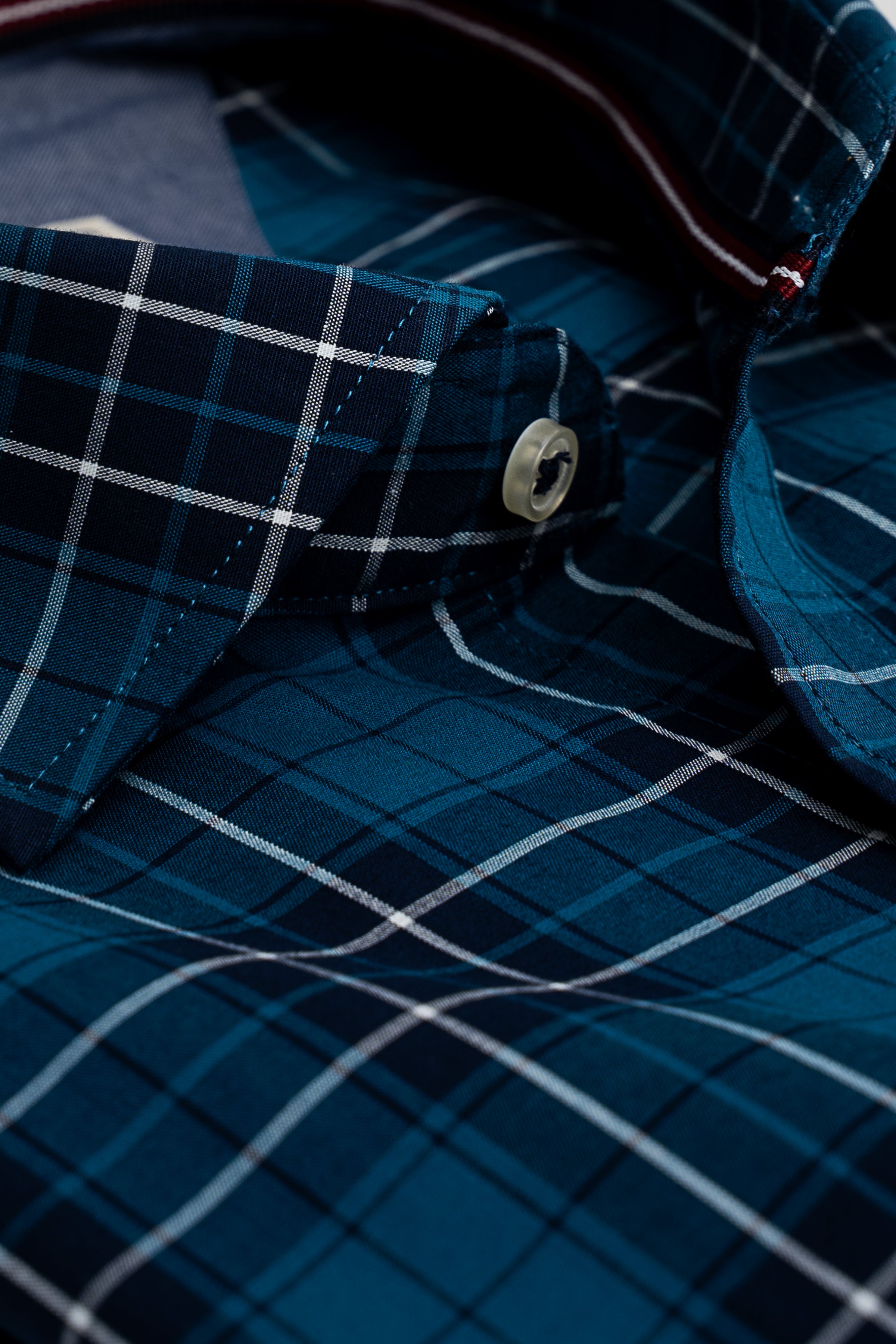 Blue check shirt cuff and button detail with contrast inner collar