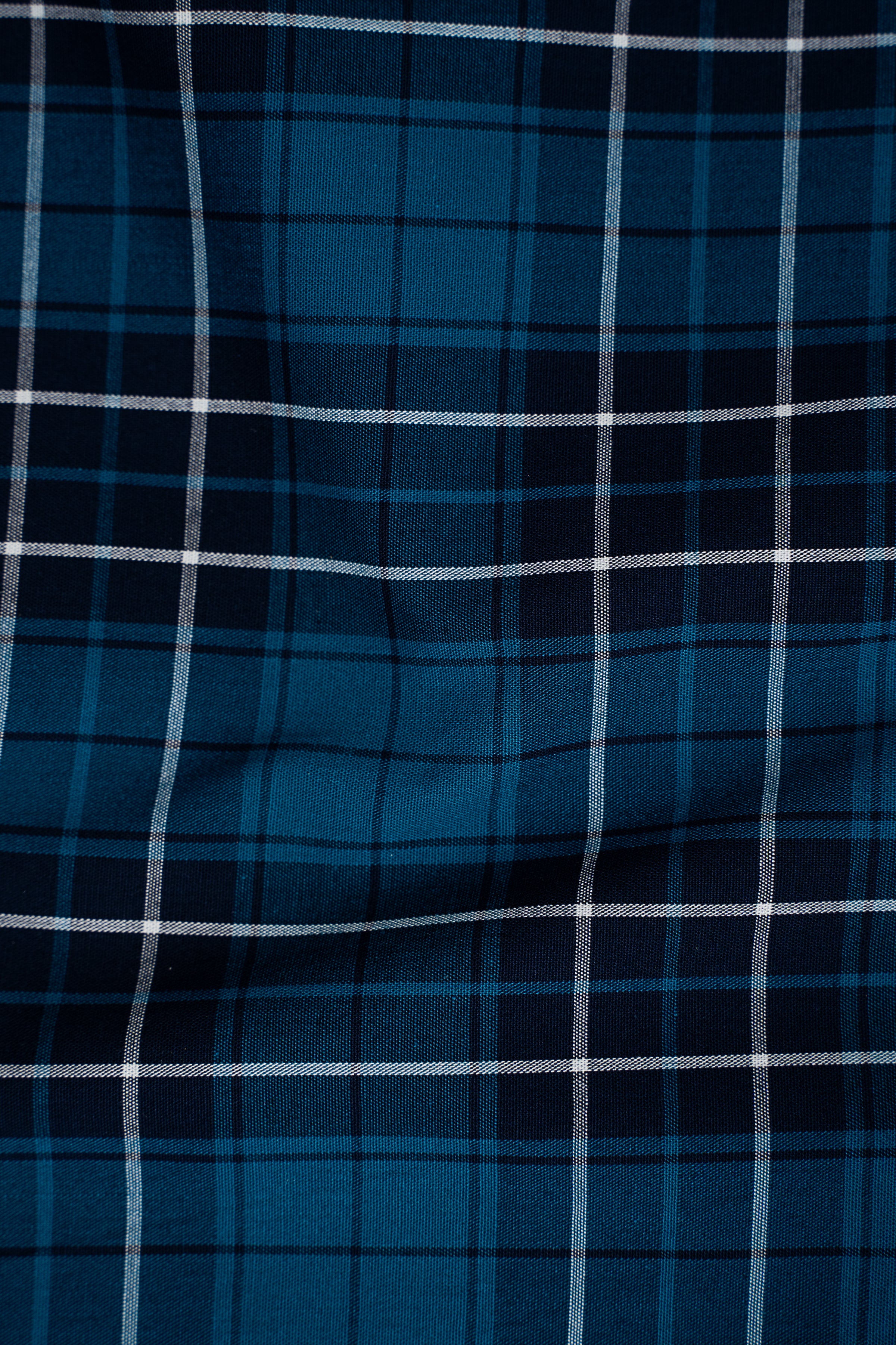 Blue check shirt fabric close-up with vertical and horizontal grid pattern
