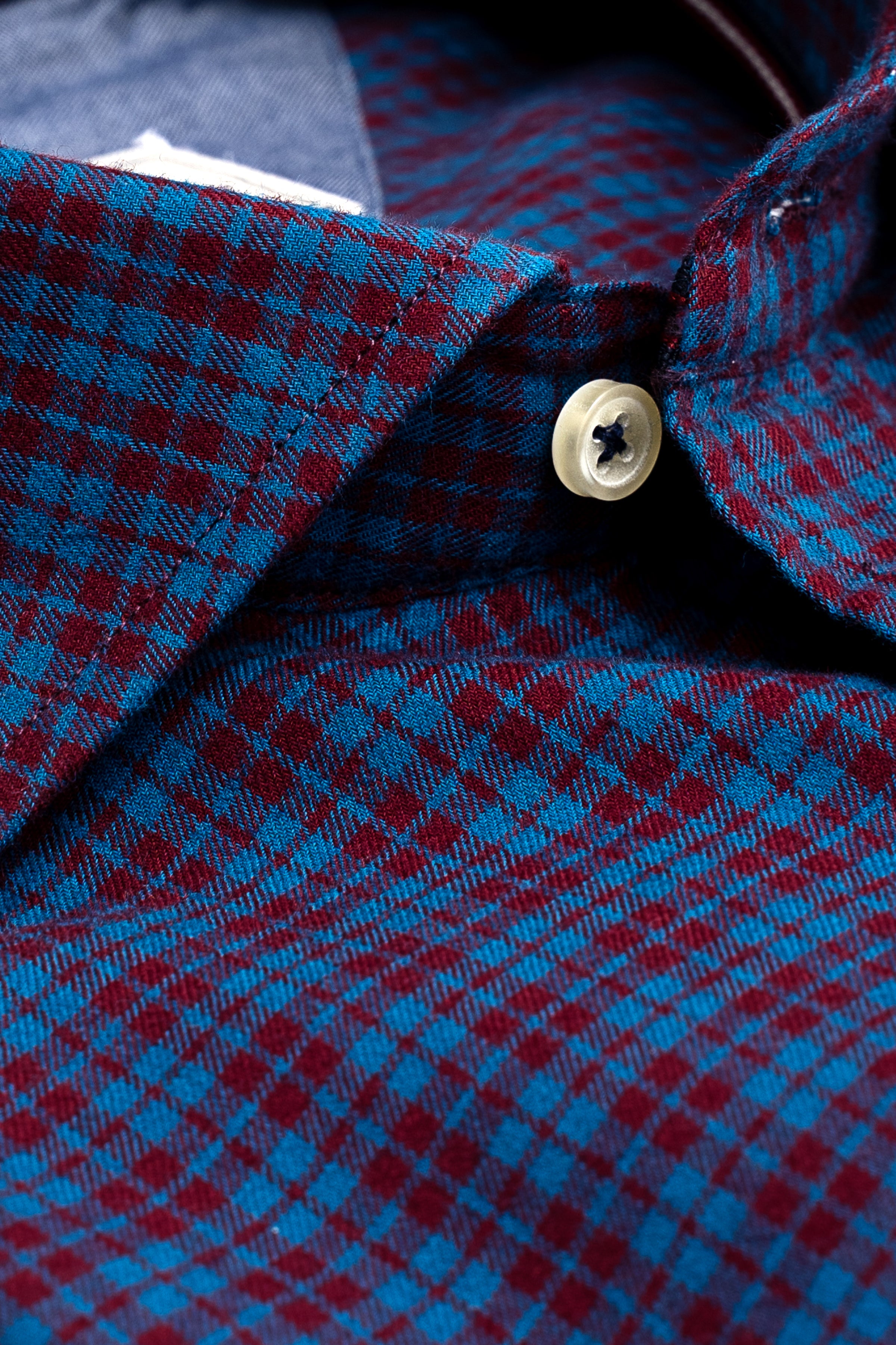 Blue and maroon check shirt collar detail with white button
