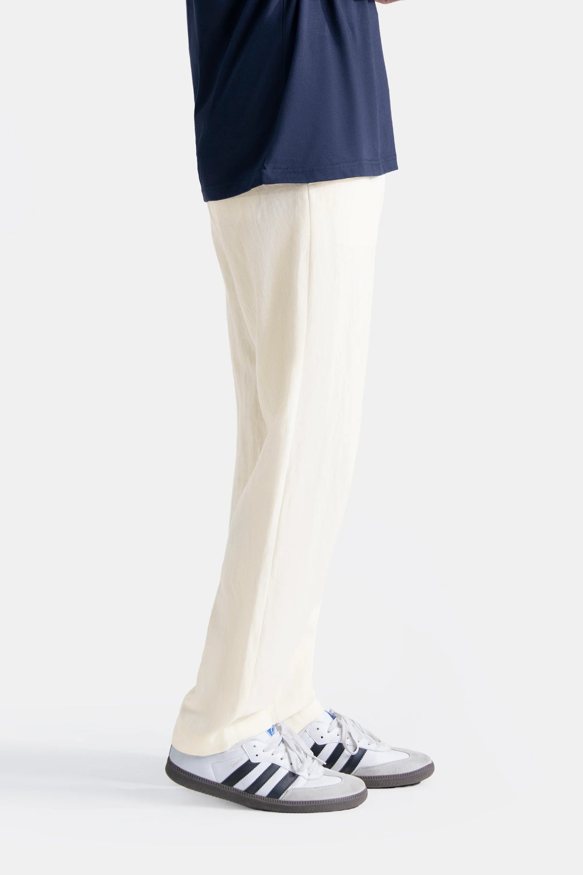 Off-white straight-leg pants on model, side view with low-top sneakers