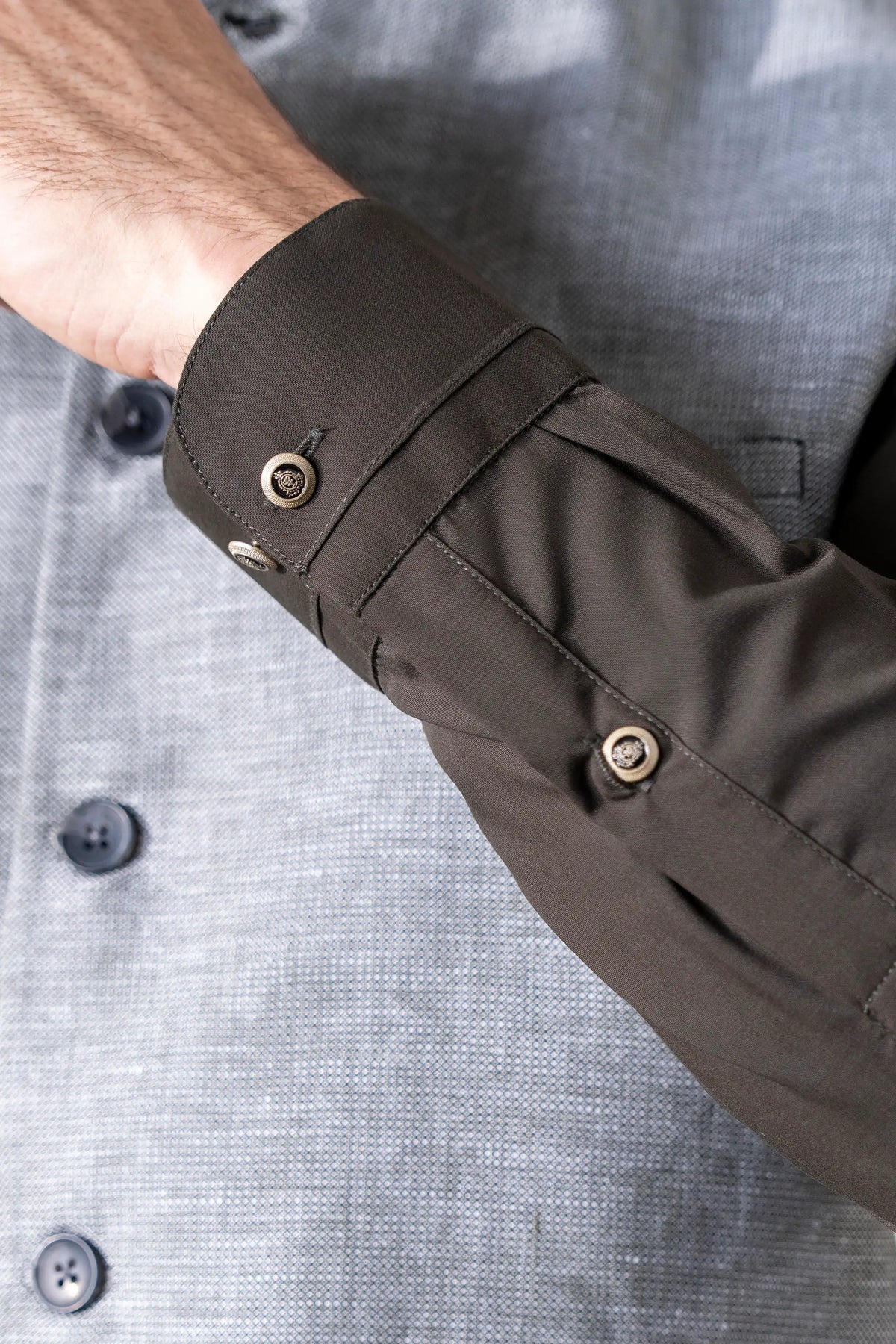 Dark sleeve cuff with button detail on light gray cotton-linen waistcoat