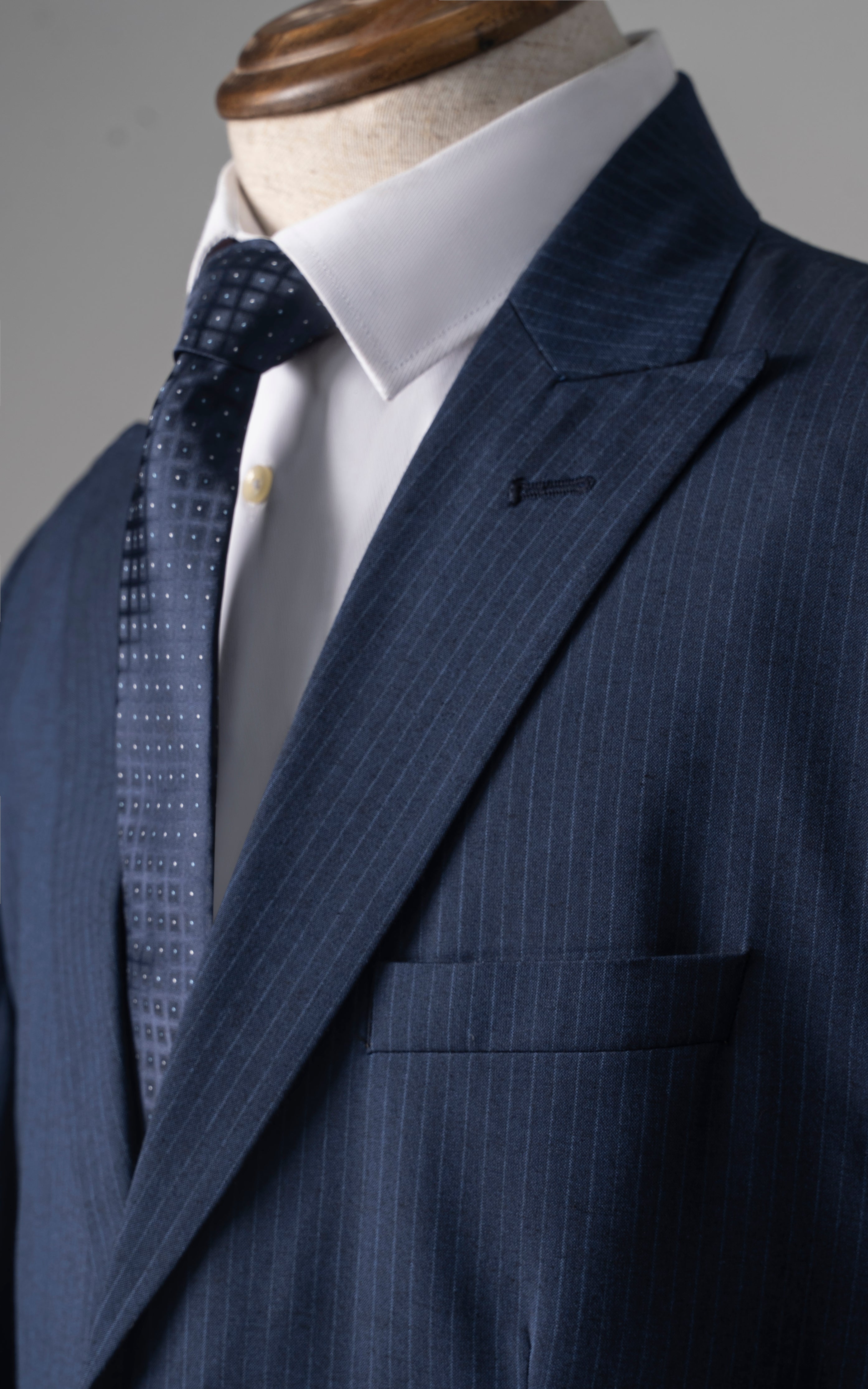 Navy pinstripe suit jacket lapel with white shirt and patterned dark tie