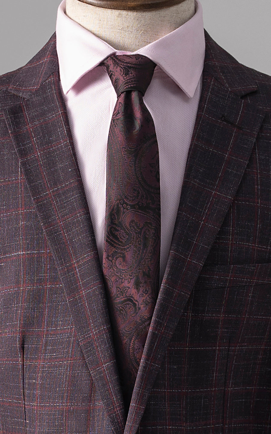 Maroon check suit jacket with white shirt collar and maroon paisley tie