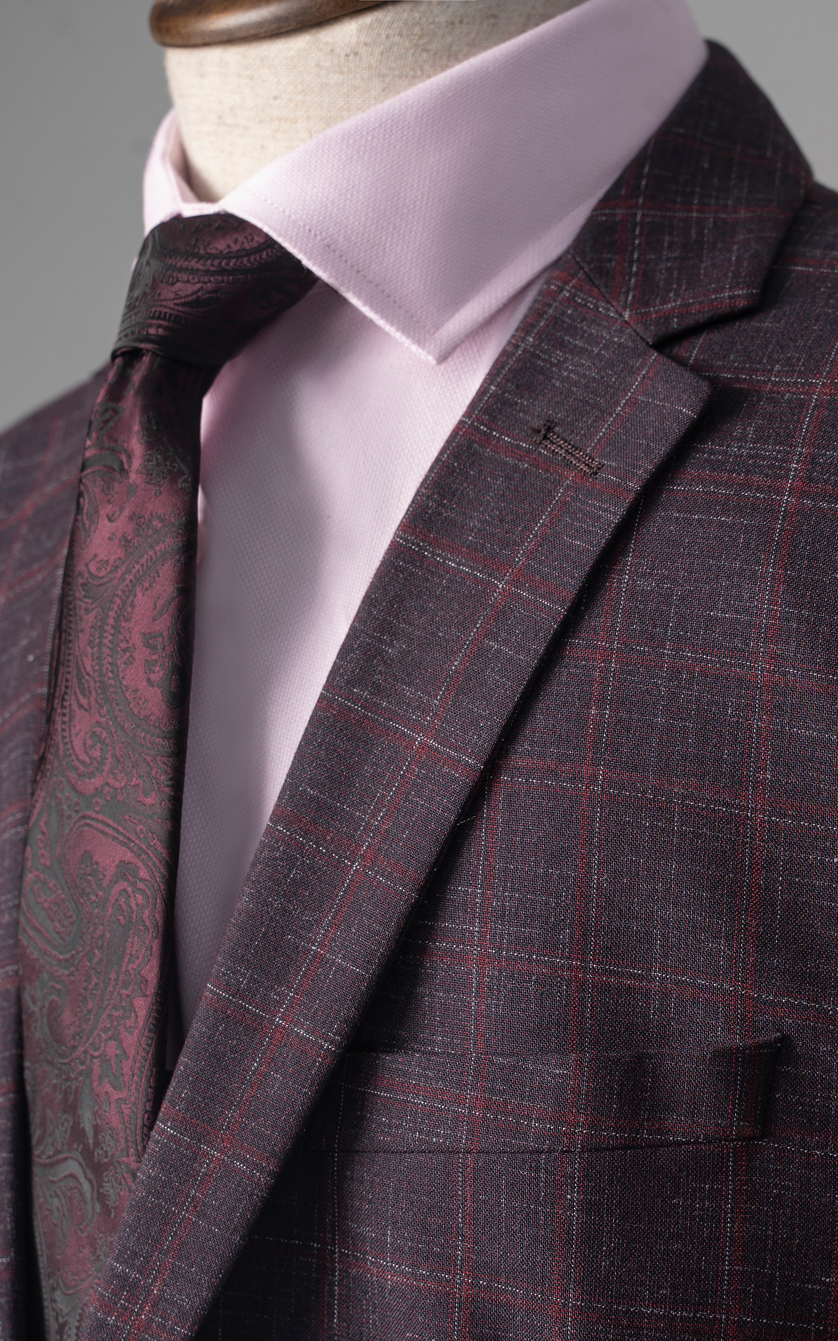 Maroon check suit jacket lapel with white shirt and patterned maroon tie