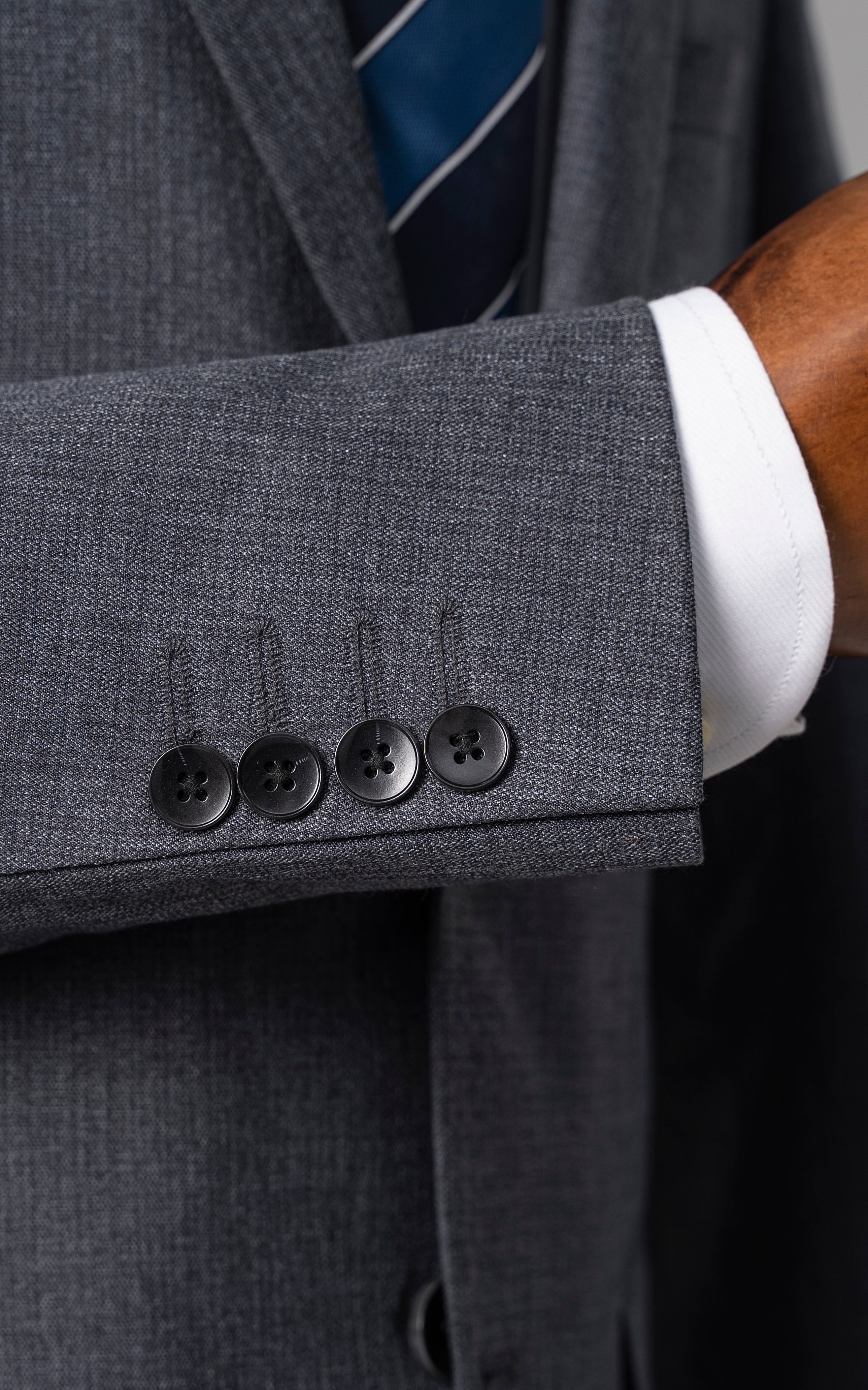 Bluish grey suit jacket sleeve cuff with four black buttons
