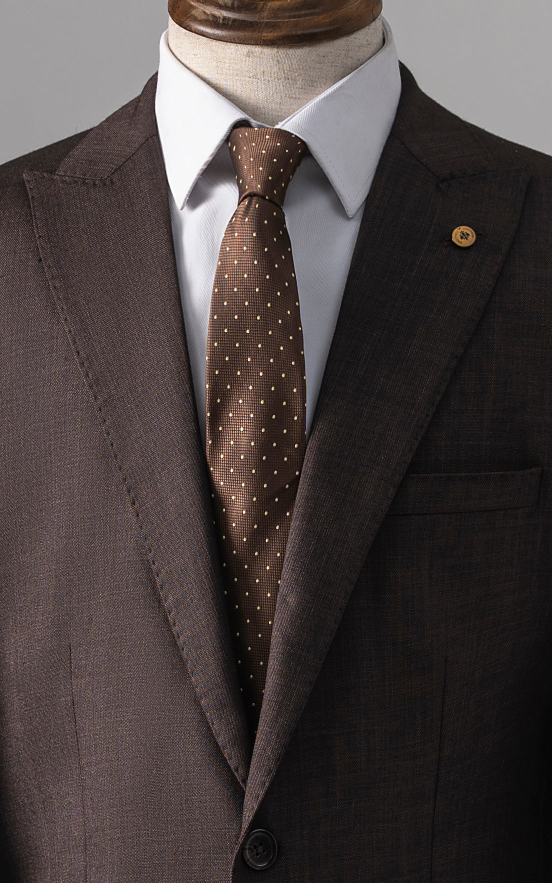 Brown two-piece suit jacket lapel with brown patterned tie and chest pocket