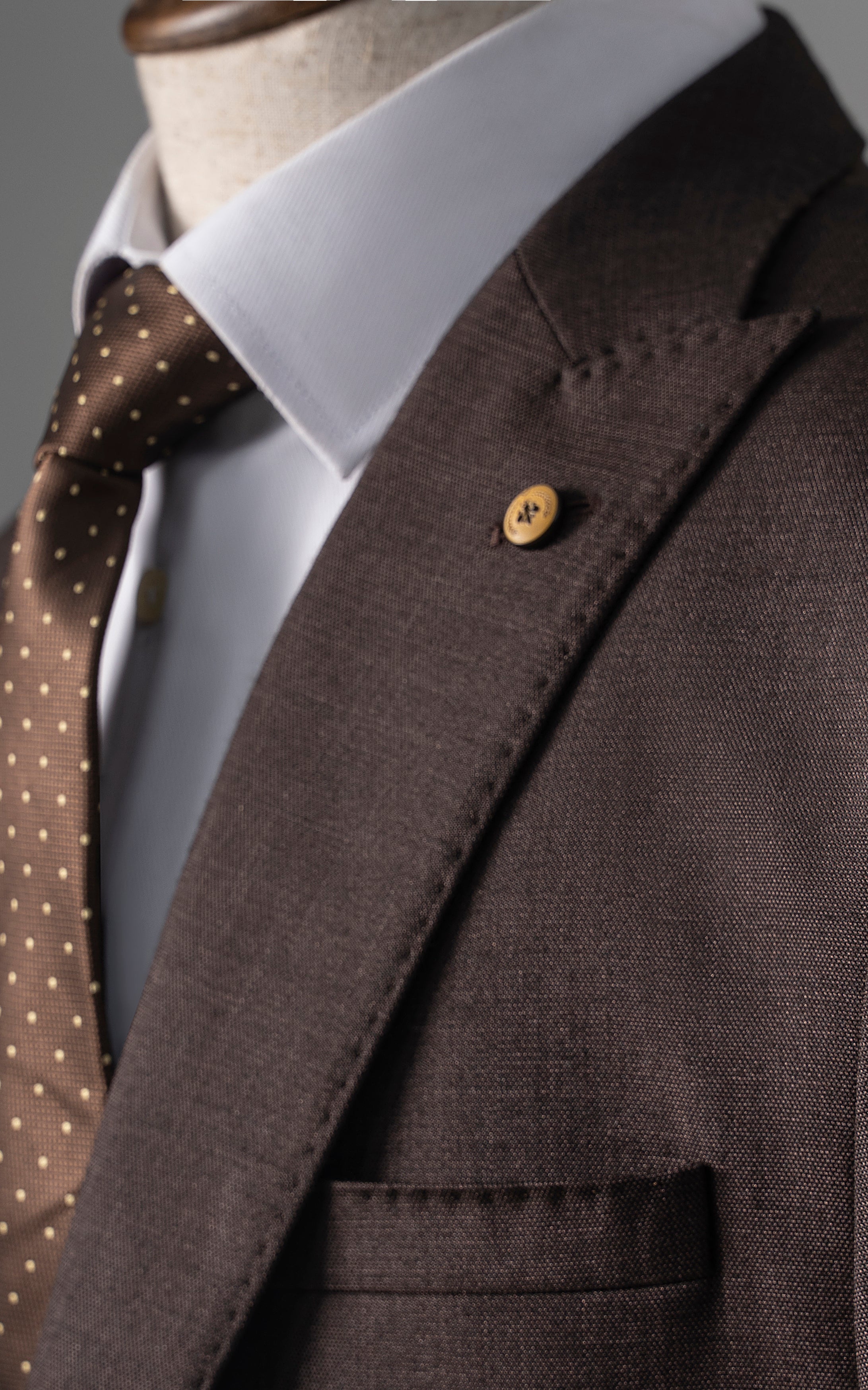 Brown two-piece suit jacket with notch lapel, chest pocket, and button detail