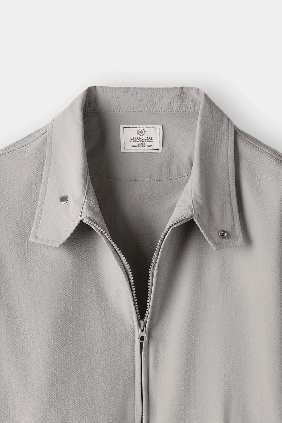 Seersucker raglan jacket close-up: stand collar, front zip, snap shoulder tabs.