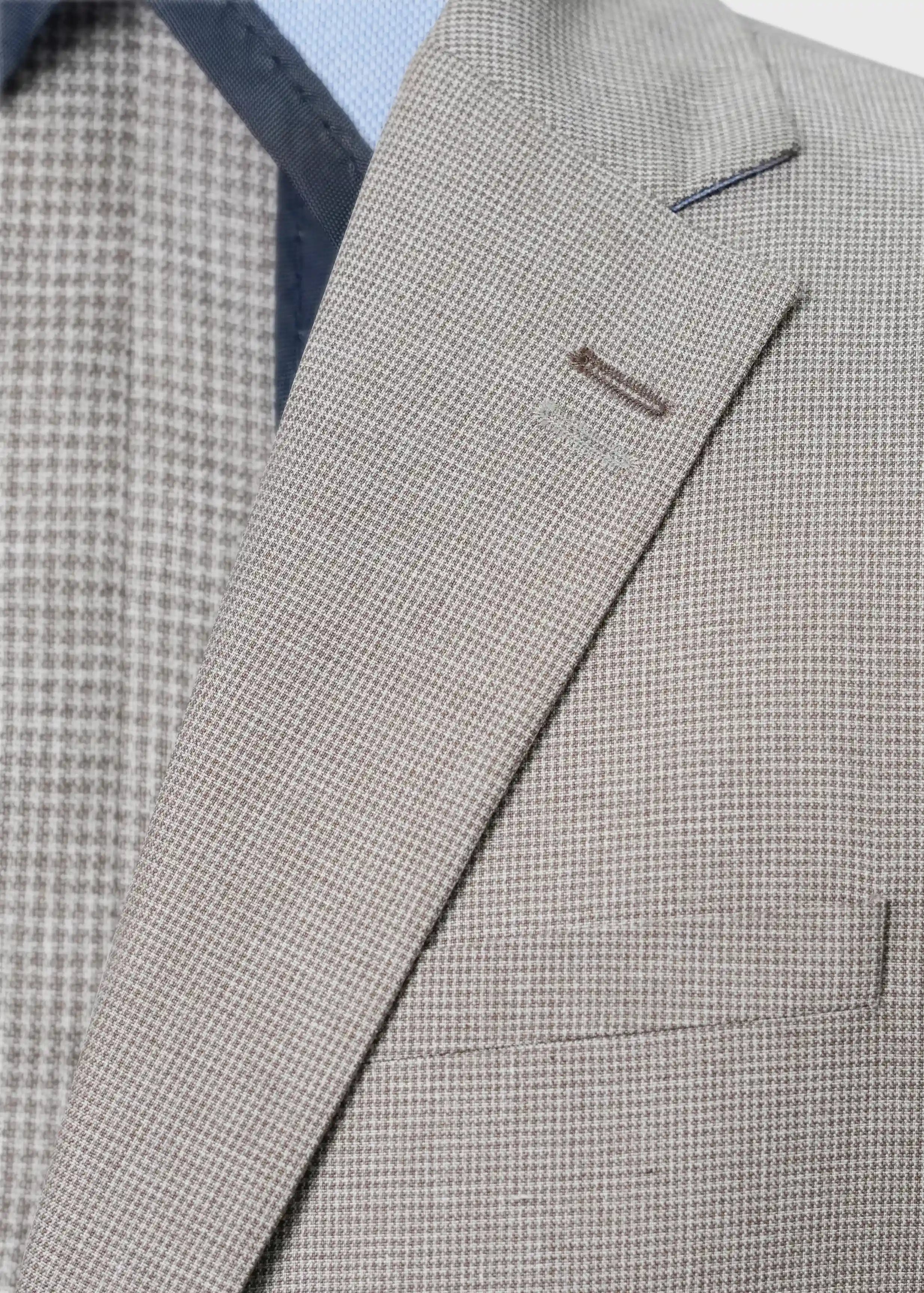 Khaki check coat close-up of lapel, welt pocket, and front buttons