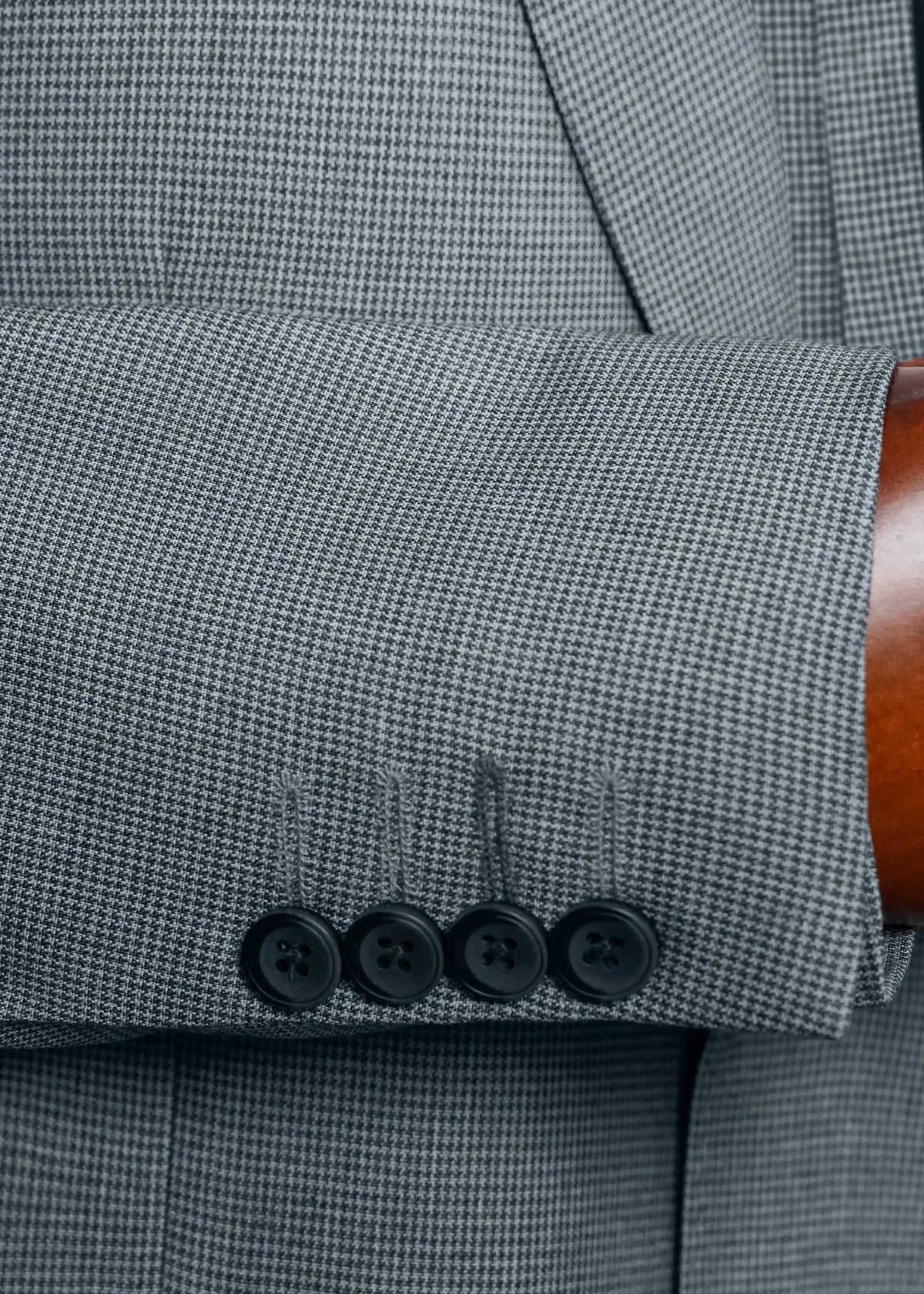 Grey houndstooth cuff with four dark buttons on casual coat sleeve